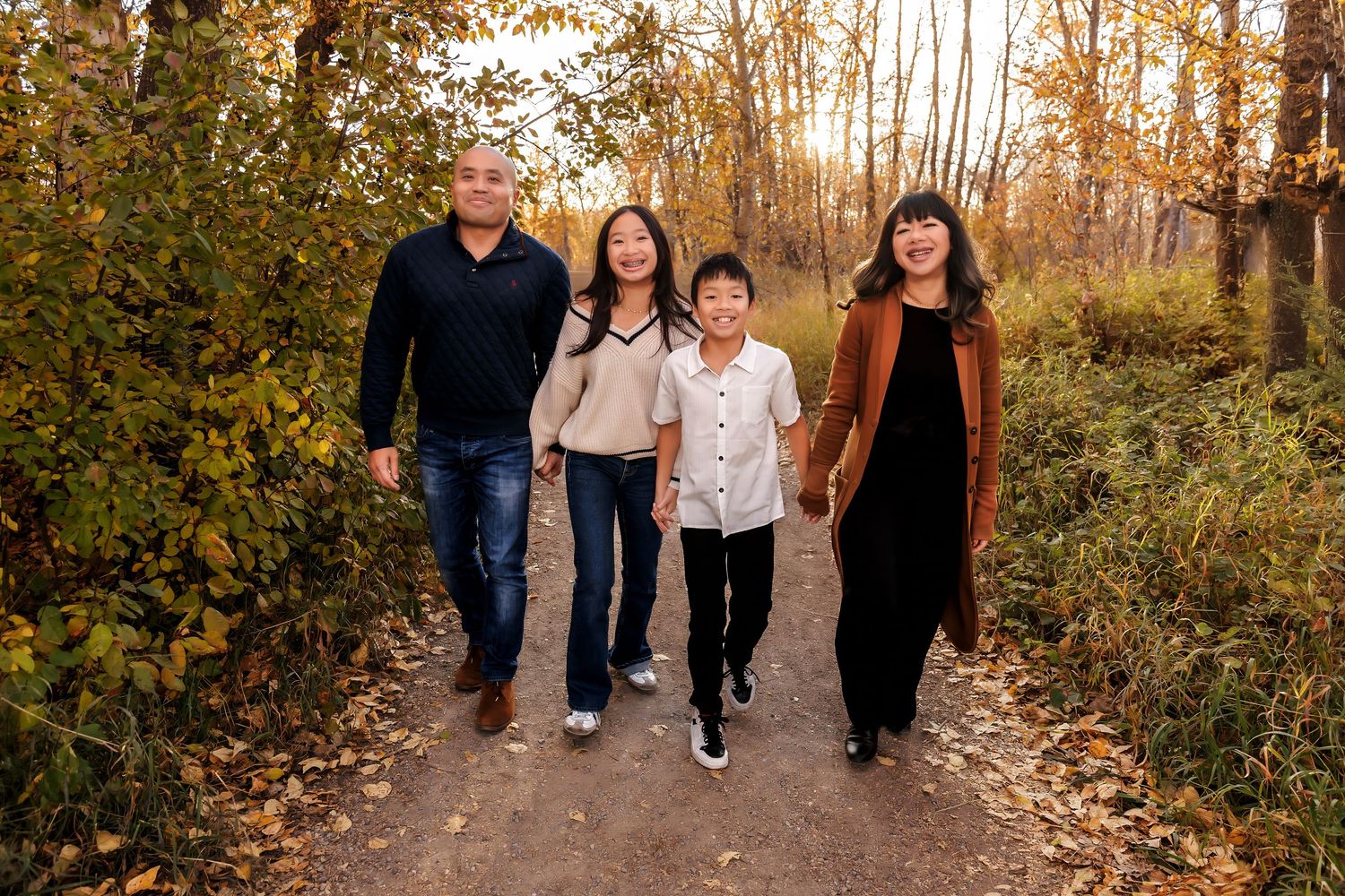 Family enjoying a fall photo session at Carburn Park in Calgary, surrounded by golden leaves and warm evening light.