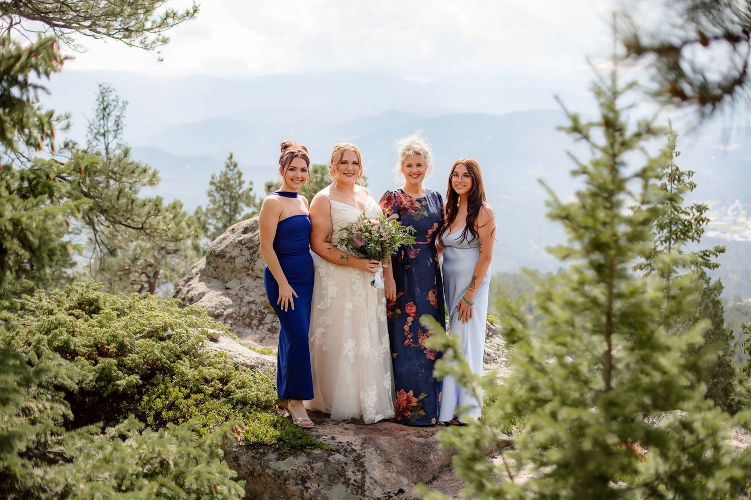 Scenic mountain wedding ceremony site with evergreen trees and dramatic cloudy skies in the background.