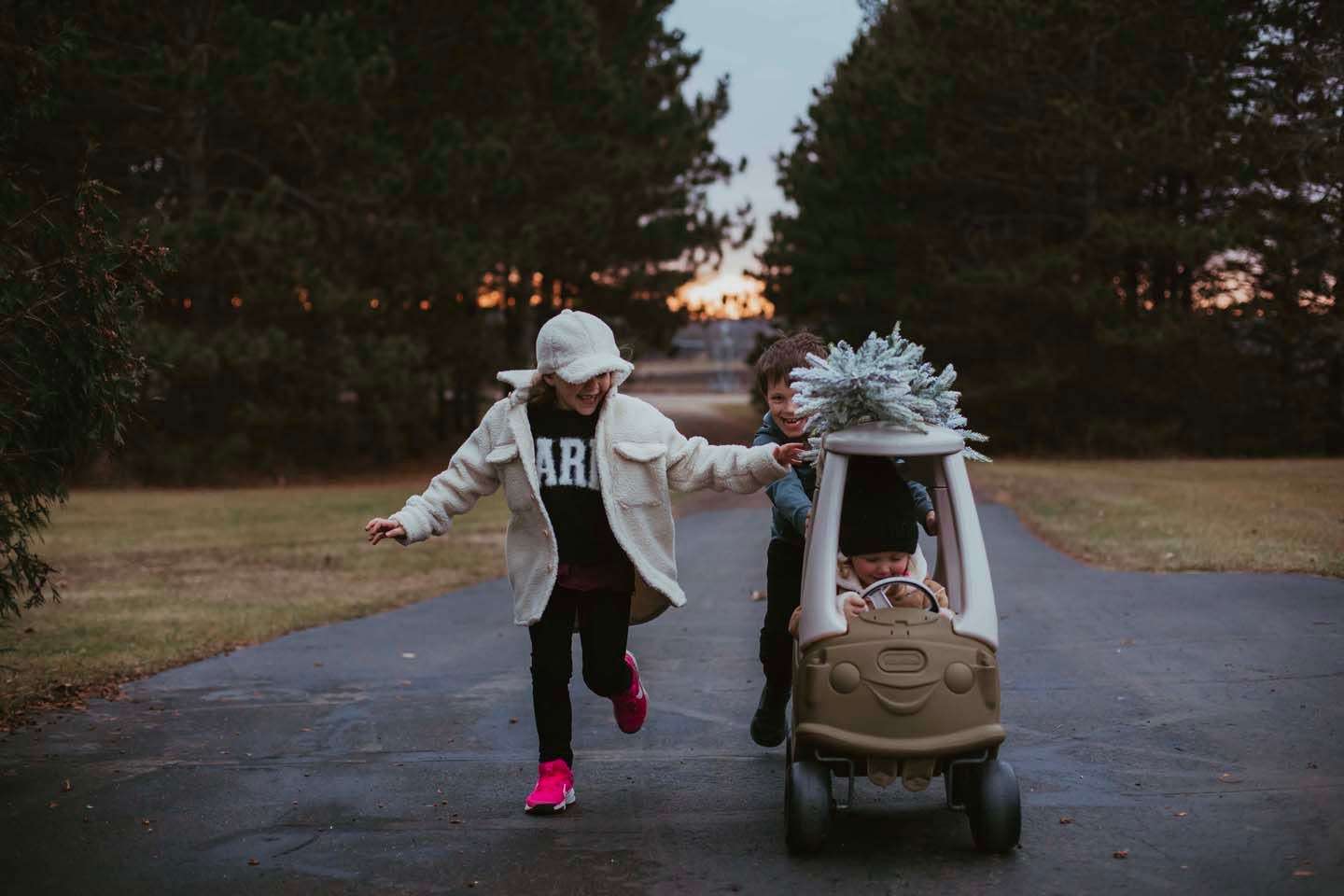 Person running alongside toy car on path at sunset.