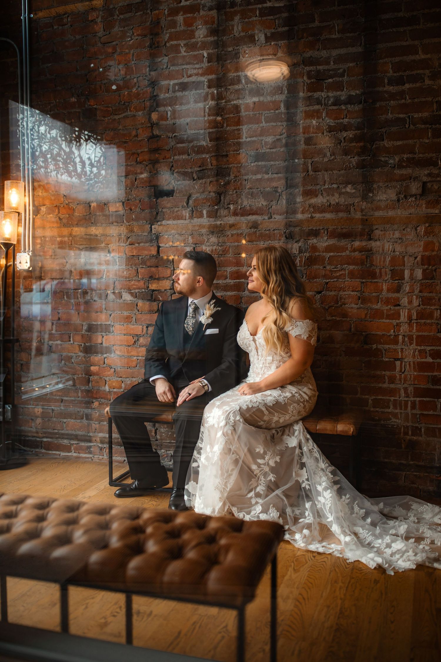 Modern wedding portrait in industrial venue with exposed brick and moody lighting.