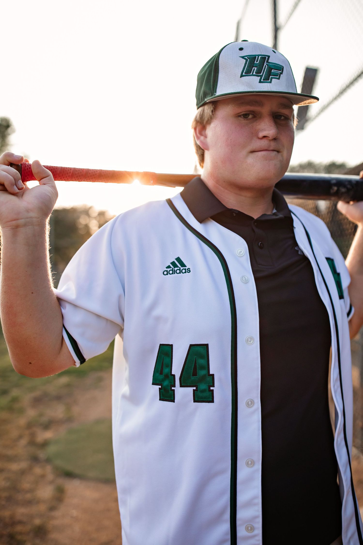 Baseball player in white jersey number 44 posing with bat at sunset.