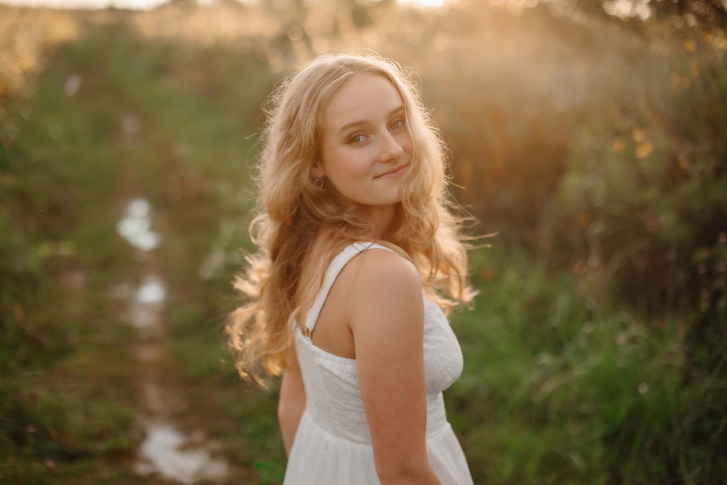 Sunset portrait in a white dress with golden light illuminating flowing hair.