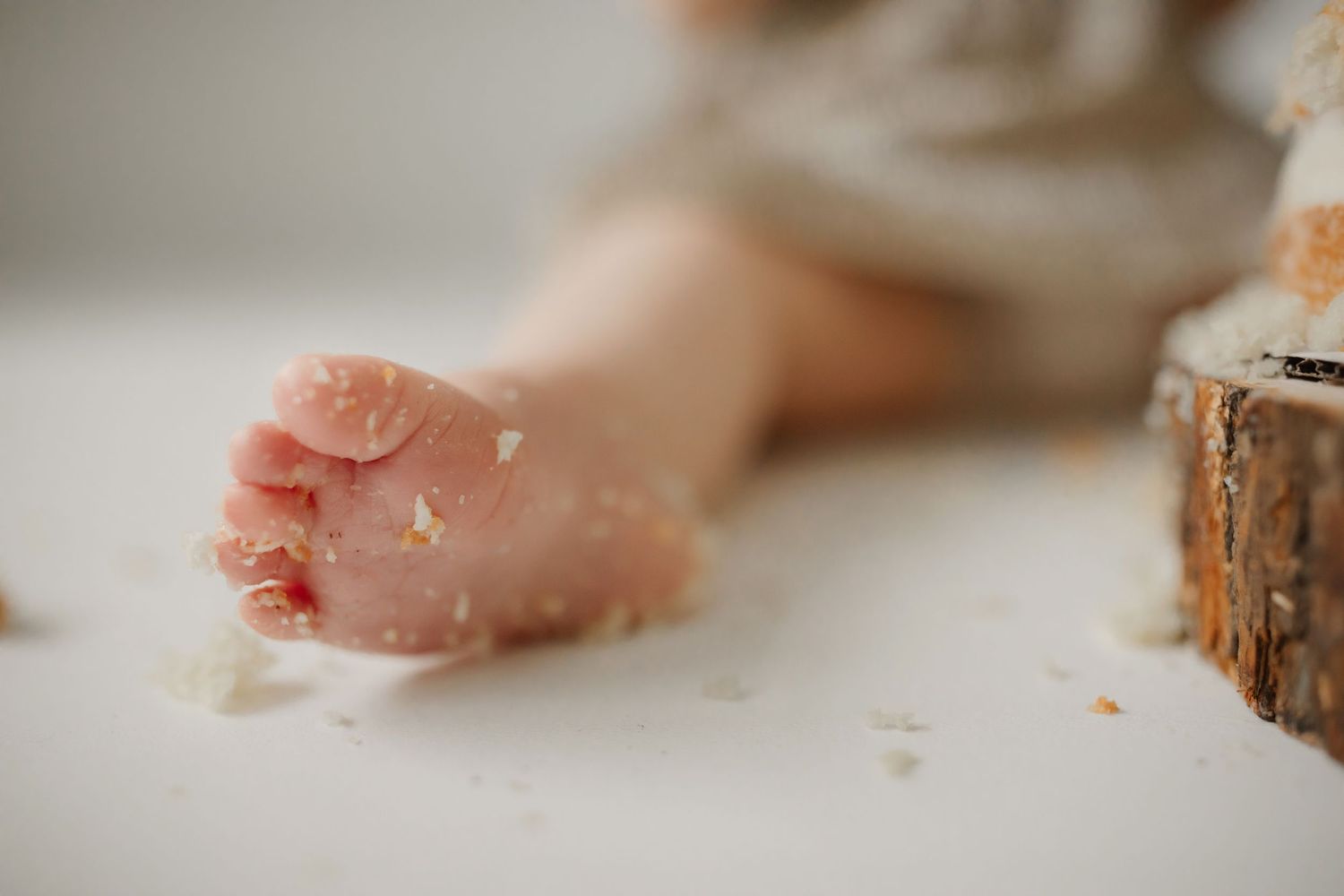 Close up of tiny foot covered in cake crumbs during first birthday photo shoot.