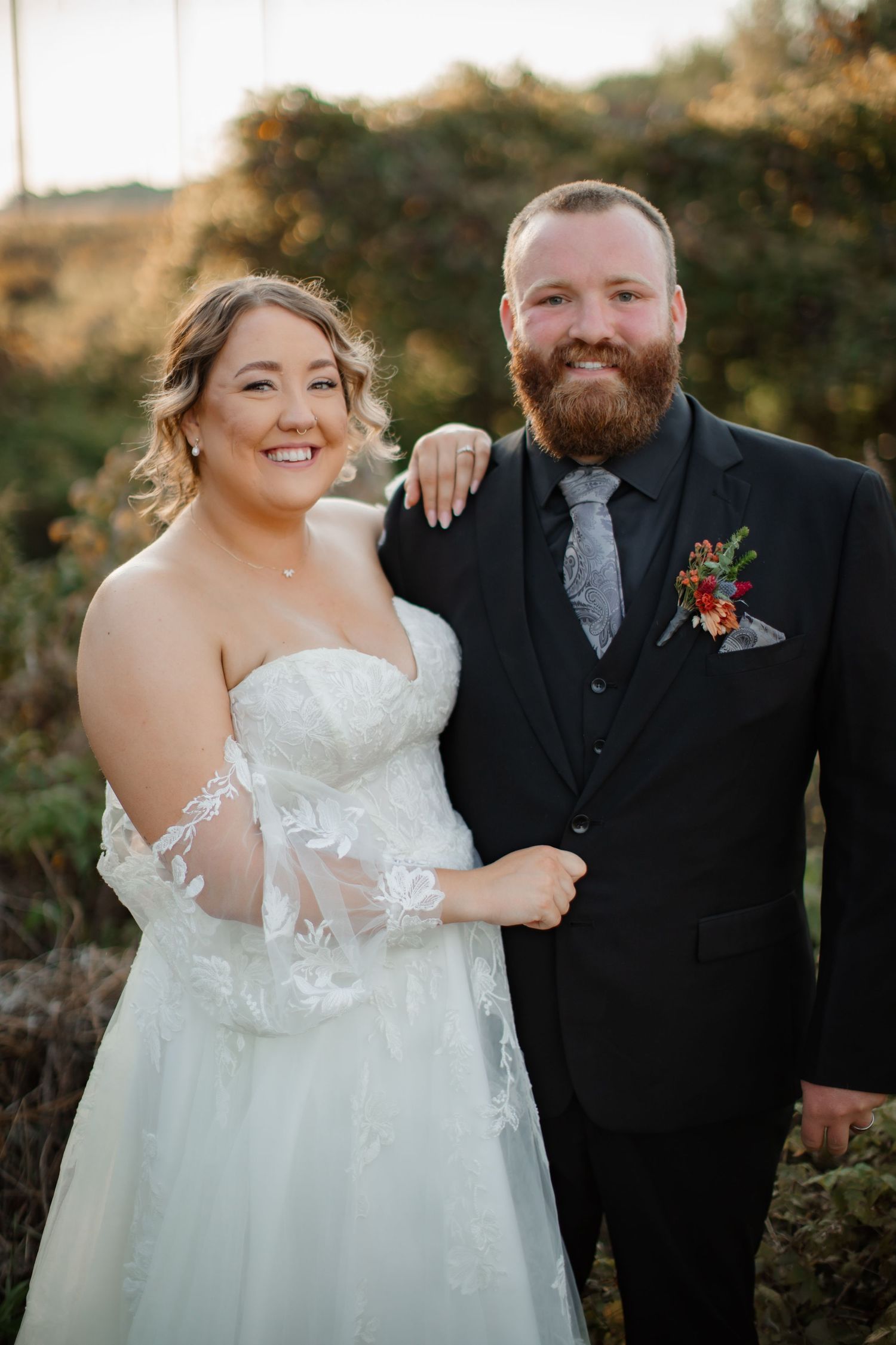 Outdoor wedding portrait of couple in formal attire during golden hour.