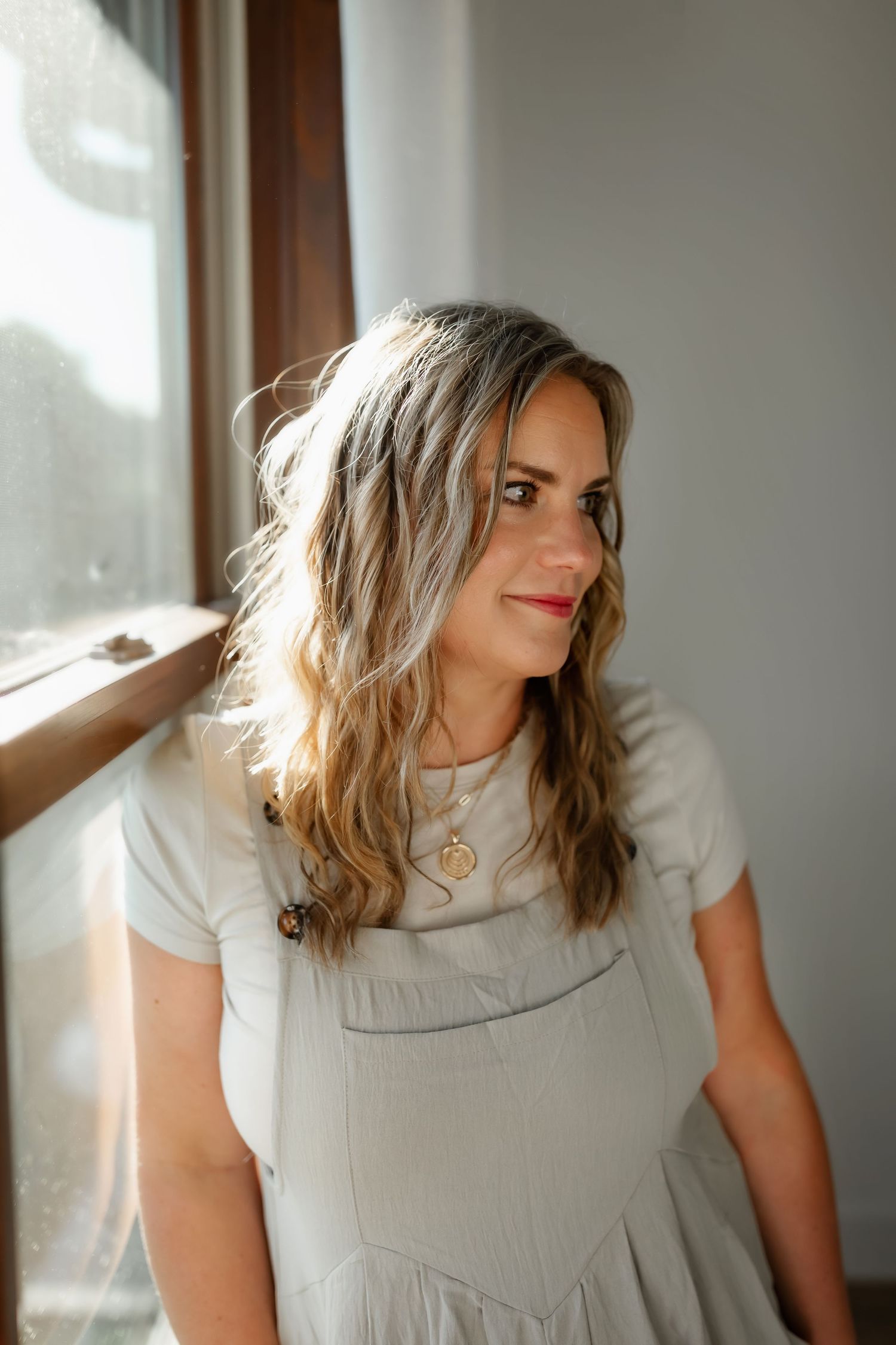 Soft window light illuminates person in white shirt and gray dress.