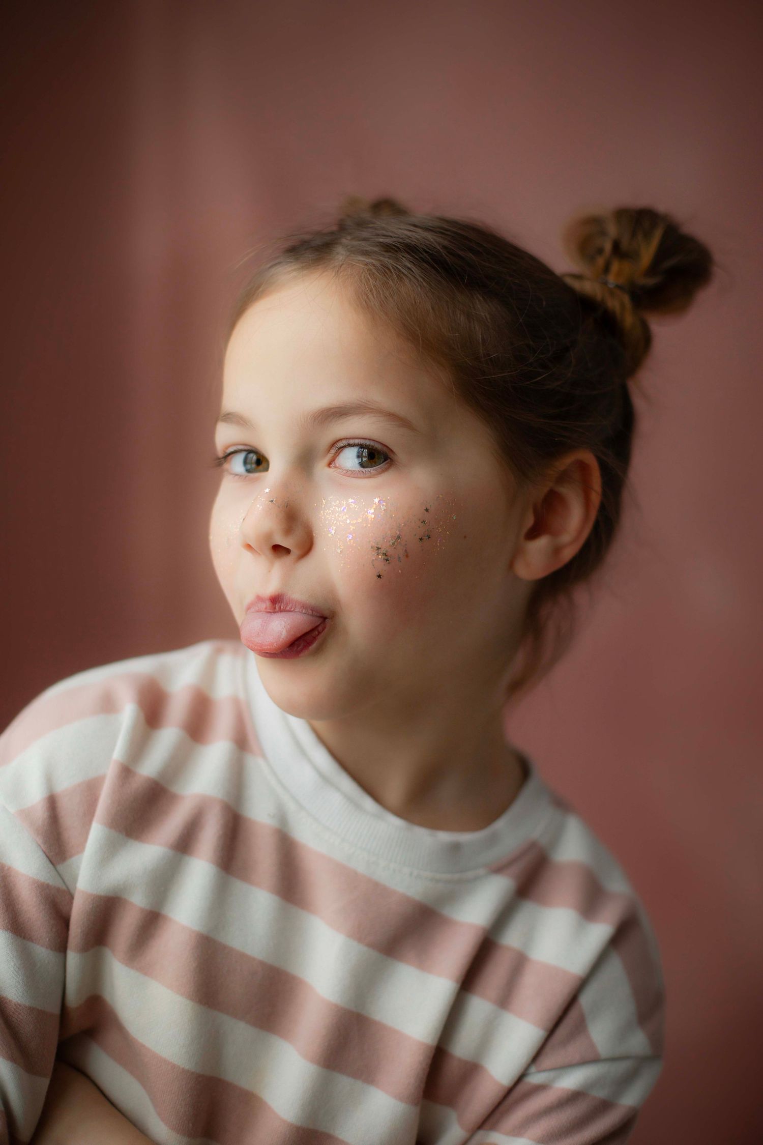A sequence of close-up portraits featuring a child wearing a pink and white striped sweater.