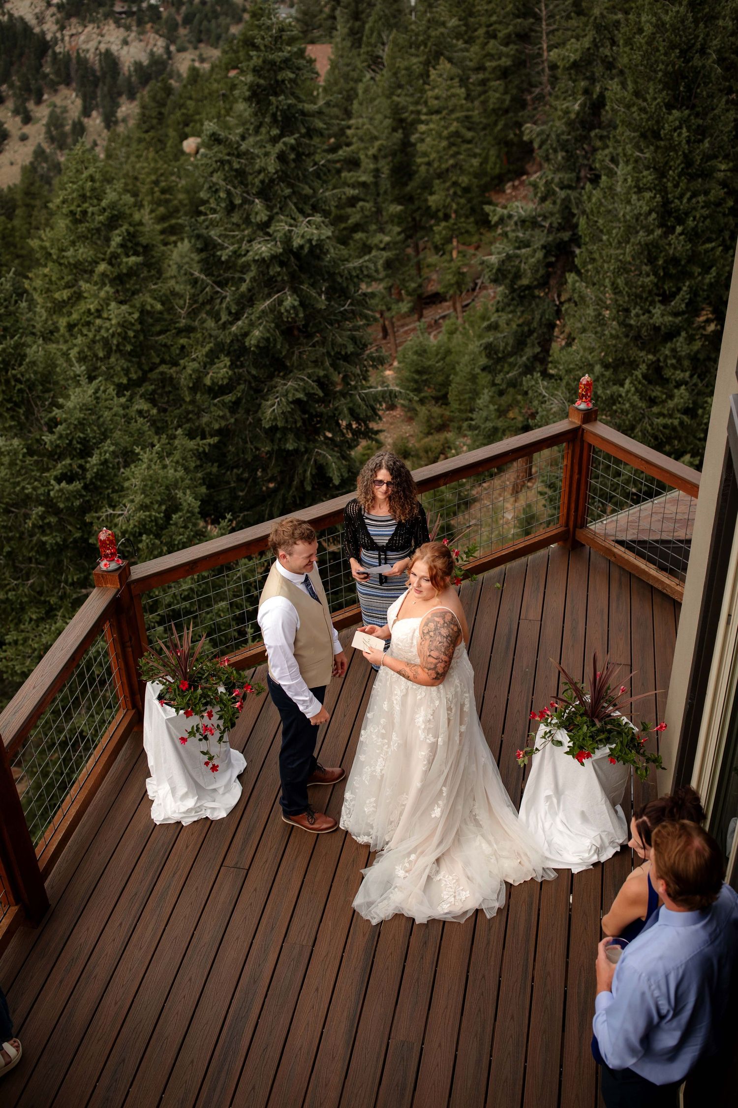 A couple shares their first dance on a scenic mountain deck surrounded by pine trees during their wedding ceremony.