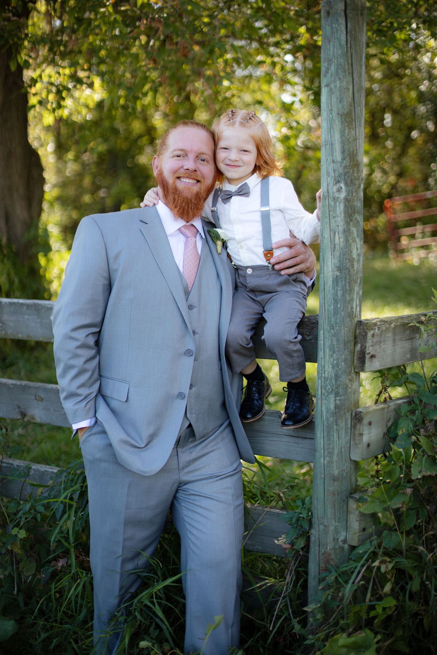 A joyful outdoor portrait by a rustic fence during an autumn wedding celebration.