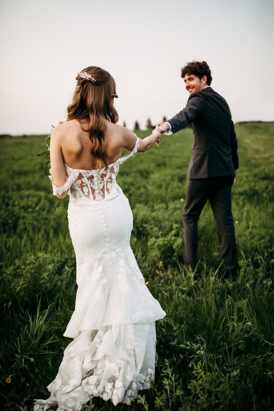 Elegant mermaid wedding dress with detailed lace back shown in outdoor portrait.