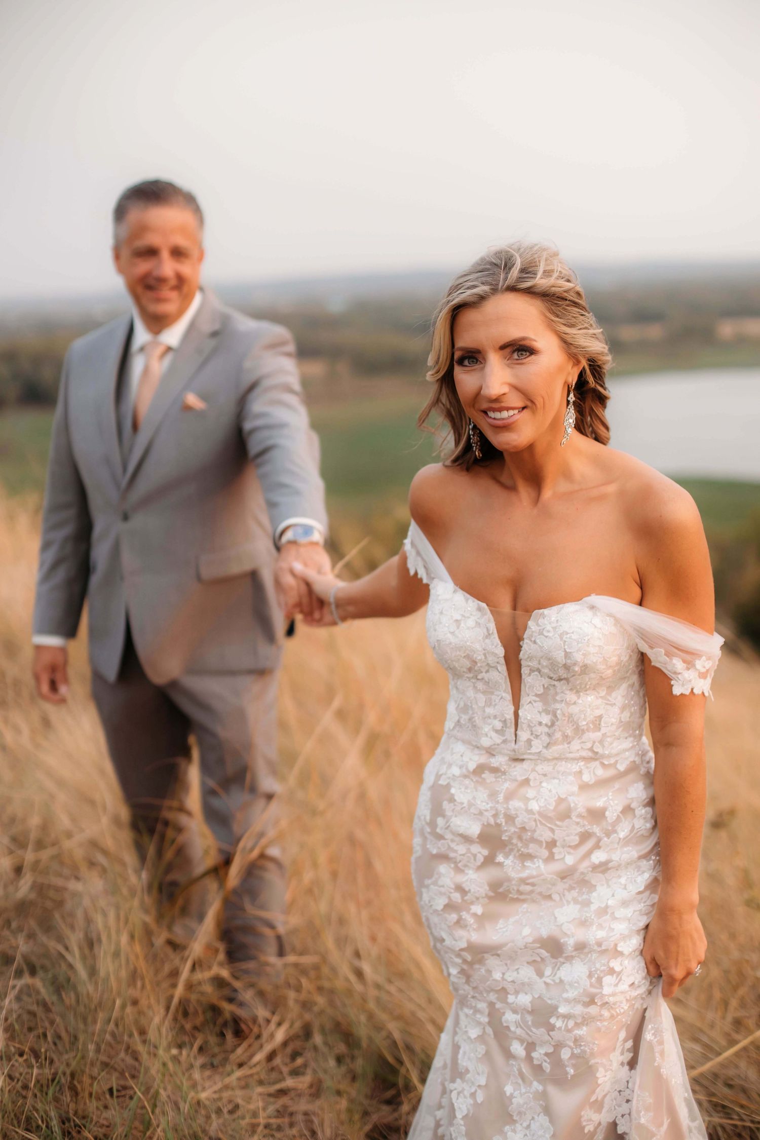 A romantic wedding portrait on a hilltop overlooking a serene lake at golden hour.