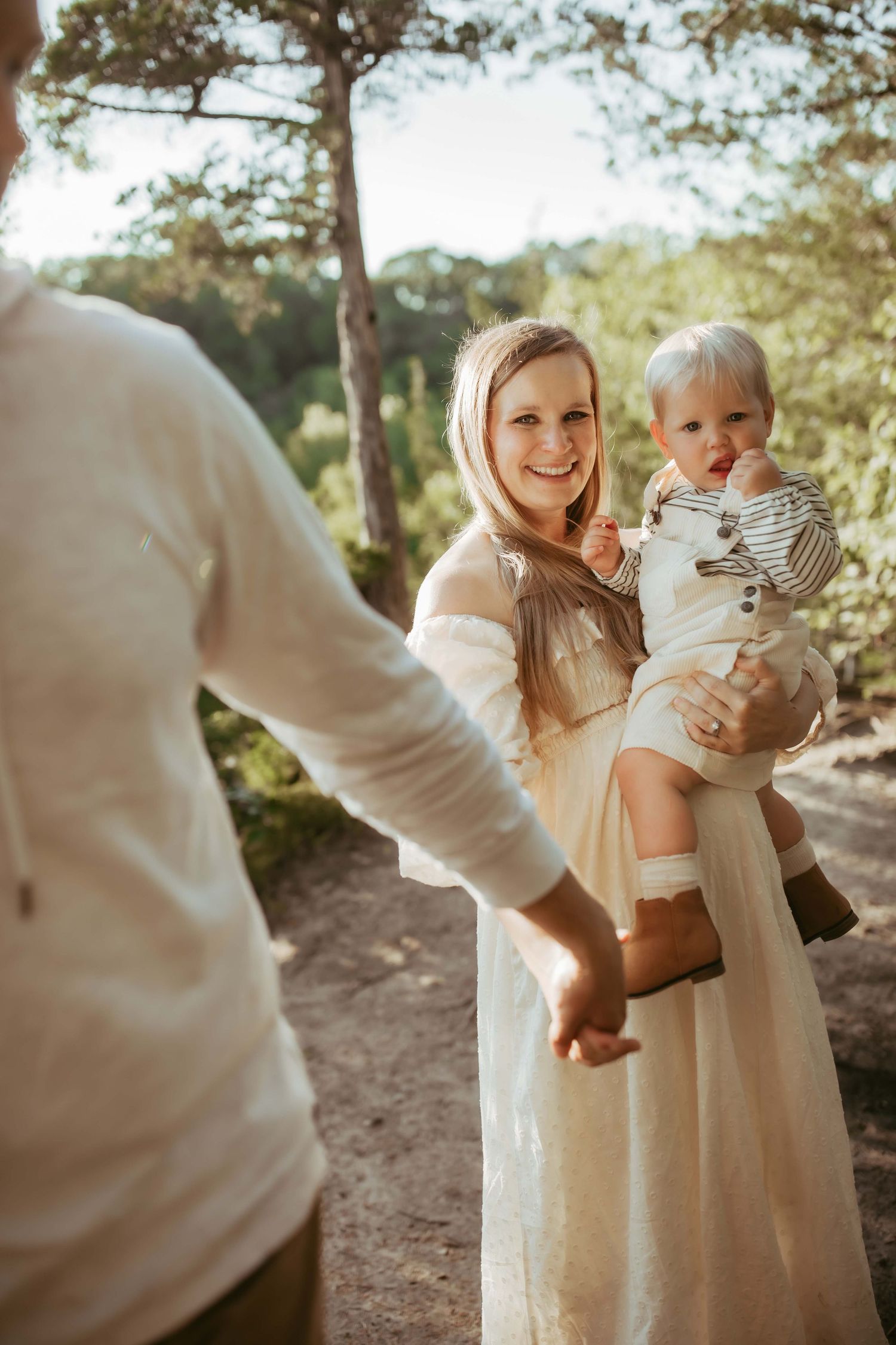 A candid family photo in nature showing joyful interaction while holding a small child.