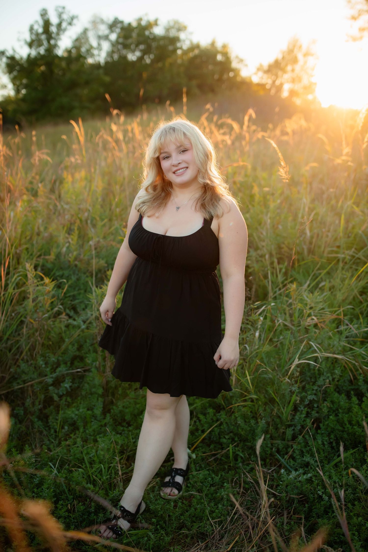 Portrait in black dress during golden hour in meadow.