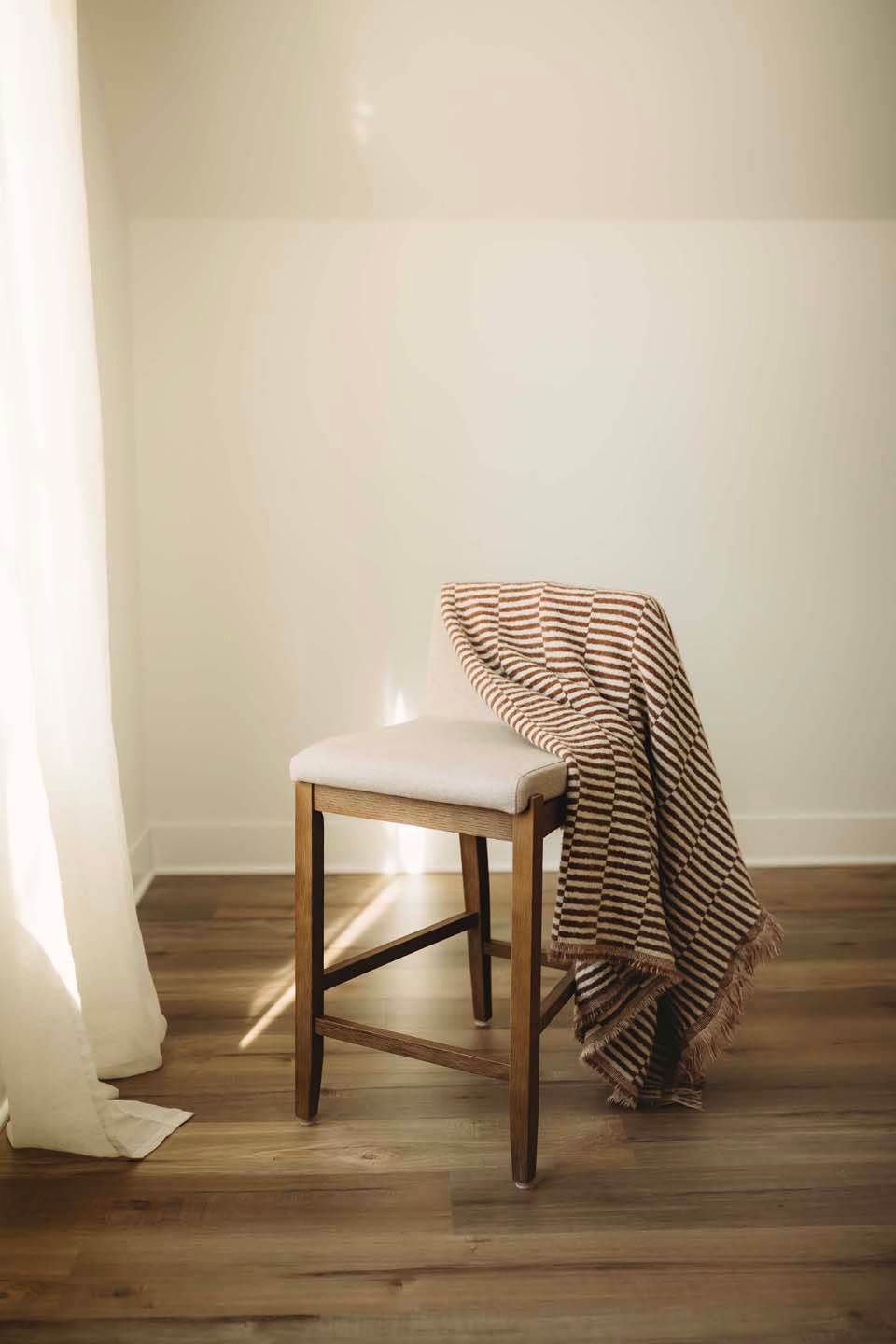 A sequence showing a wooden chair with a striped blanket gradually falling over on hardwood flooring.