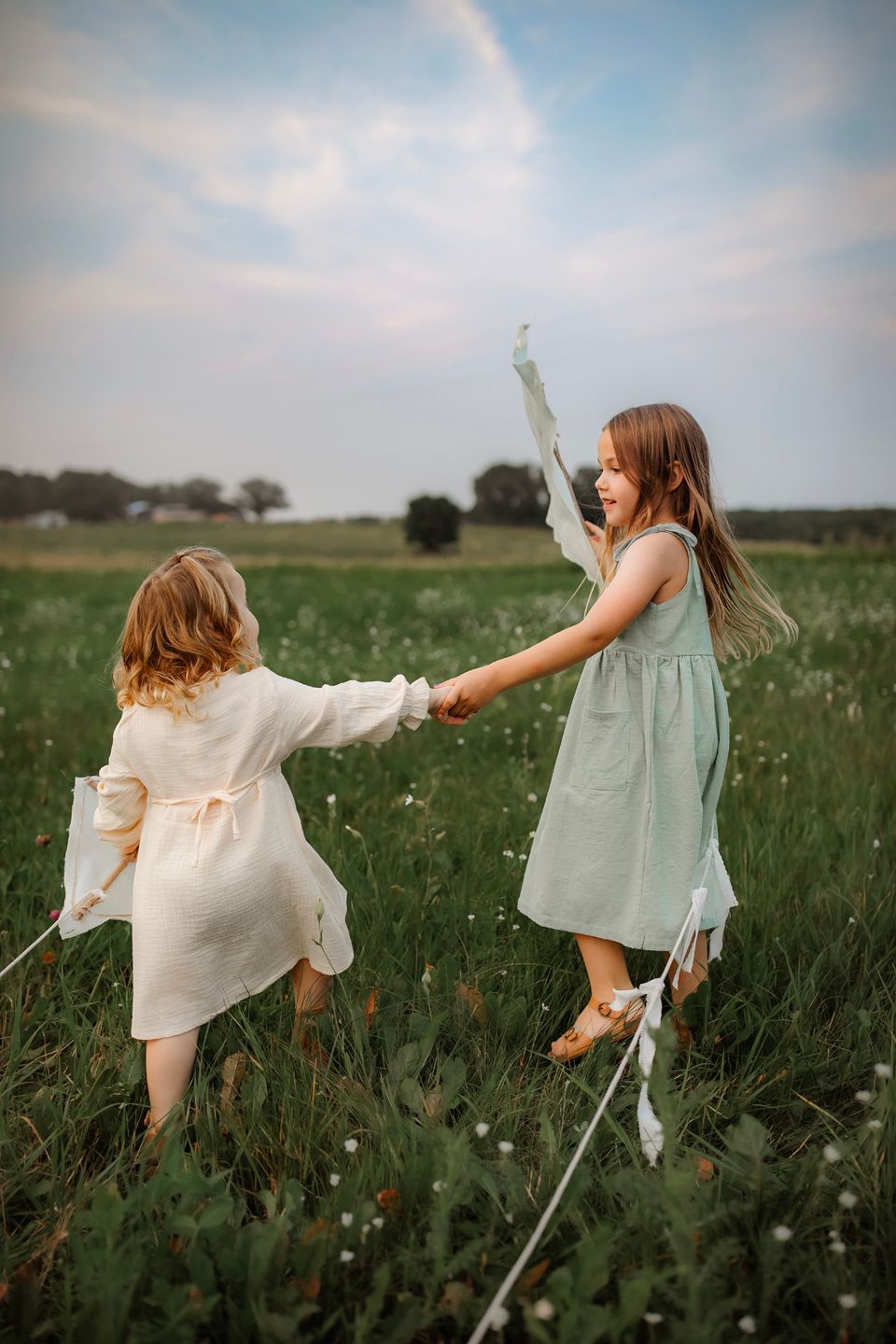 Children dancing with kites through a wildflower meadow during golden hour.