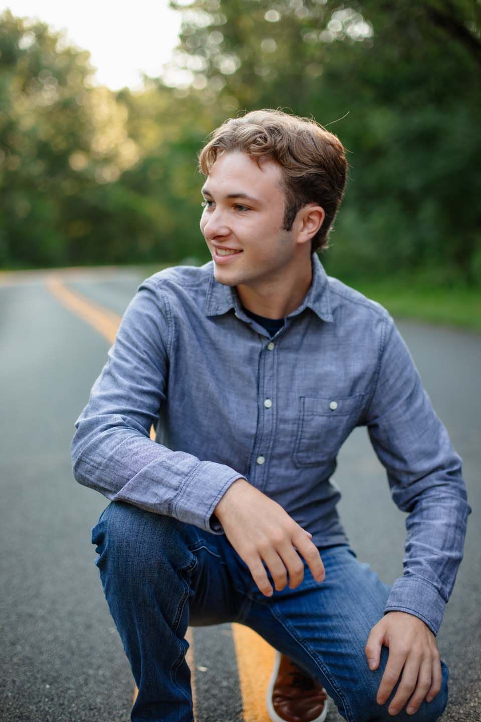 Casual portrait of person in blue button-down shirt on asphalt road.
