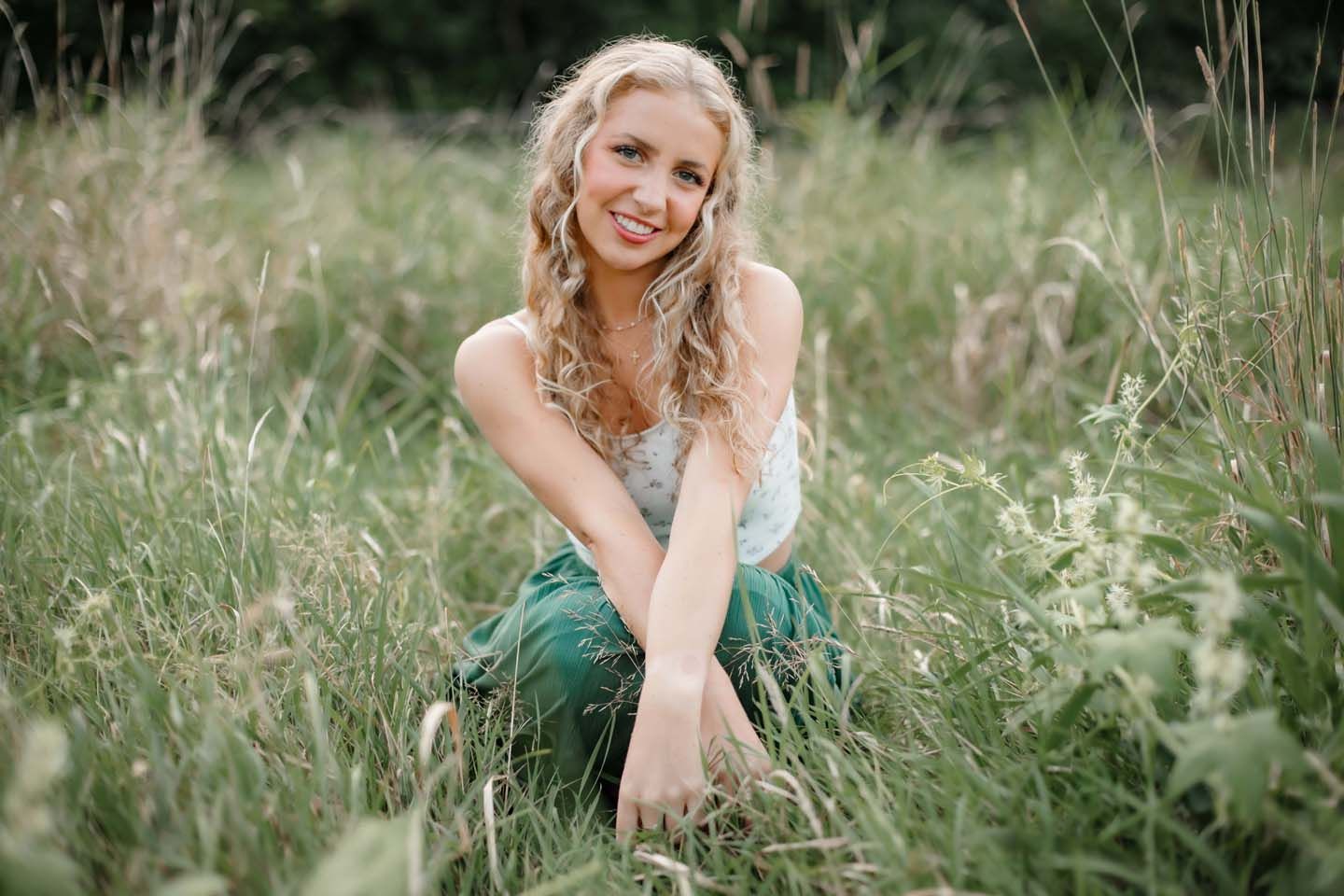 Summer portrait in tall grass wearing green skirt and white top.