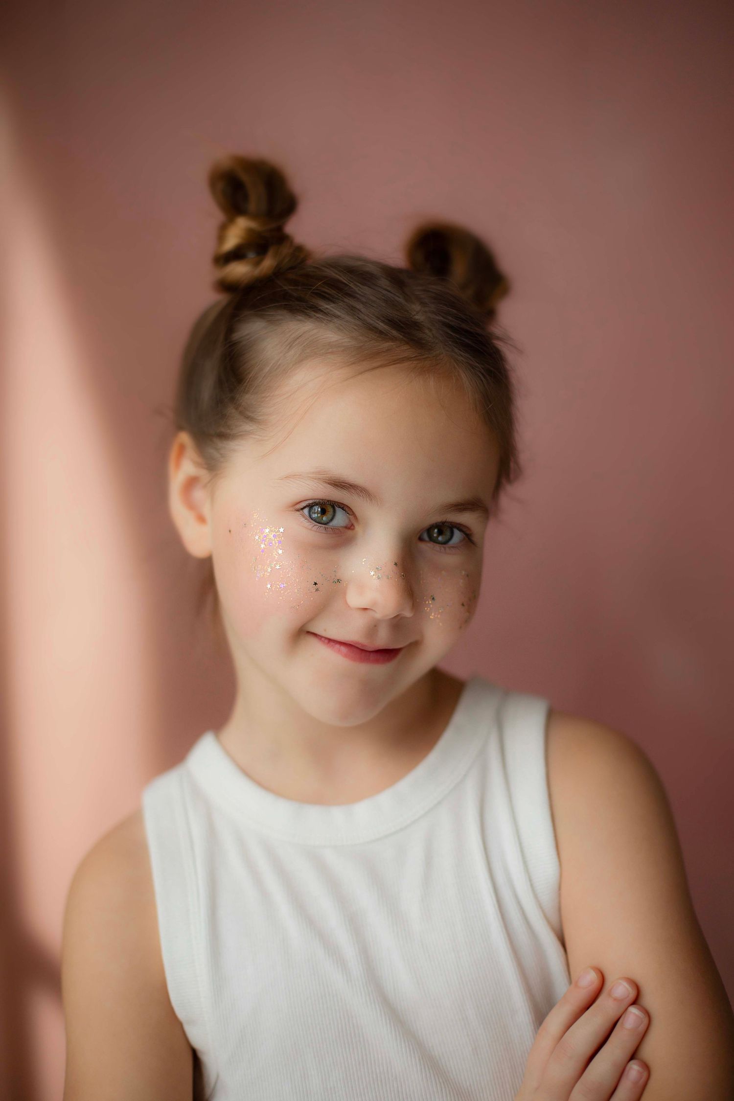 Sweet portrait series in white top against pink background showing playful expressions and gentle smiles.