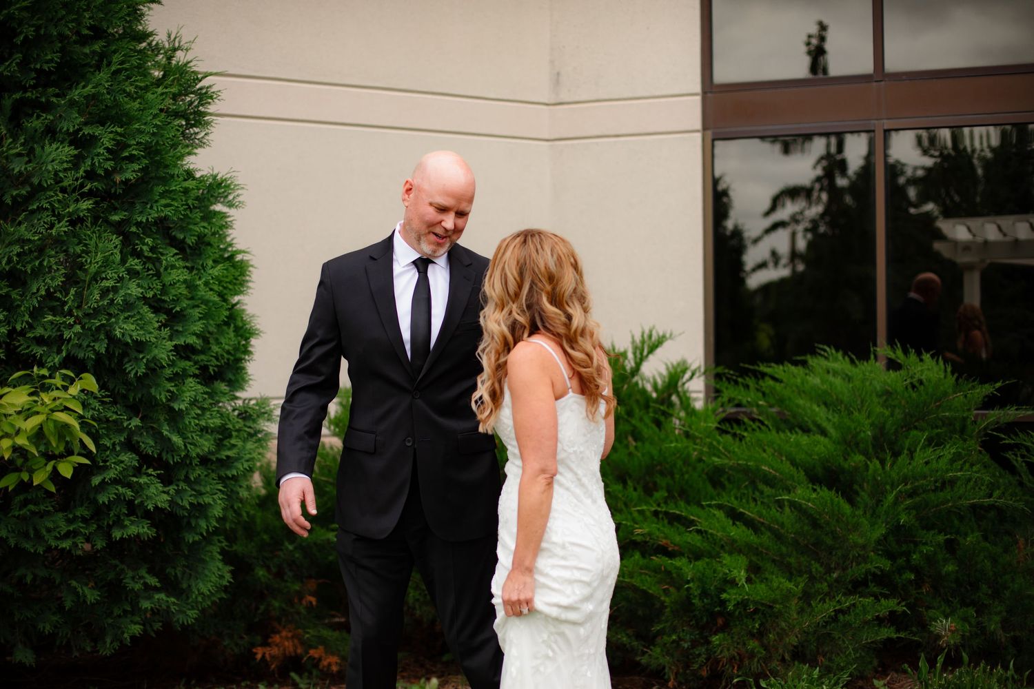 A couple shares a romantic moment in a garden setting with lush green foliage surrounding them.