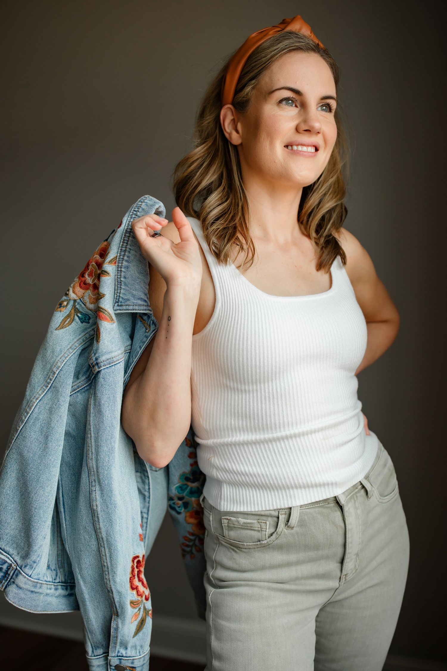 Styled fashion photo featuring embroidered denim jacket, white tank top and orange headband.