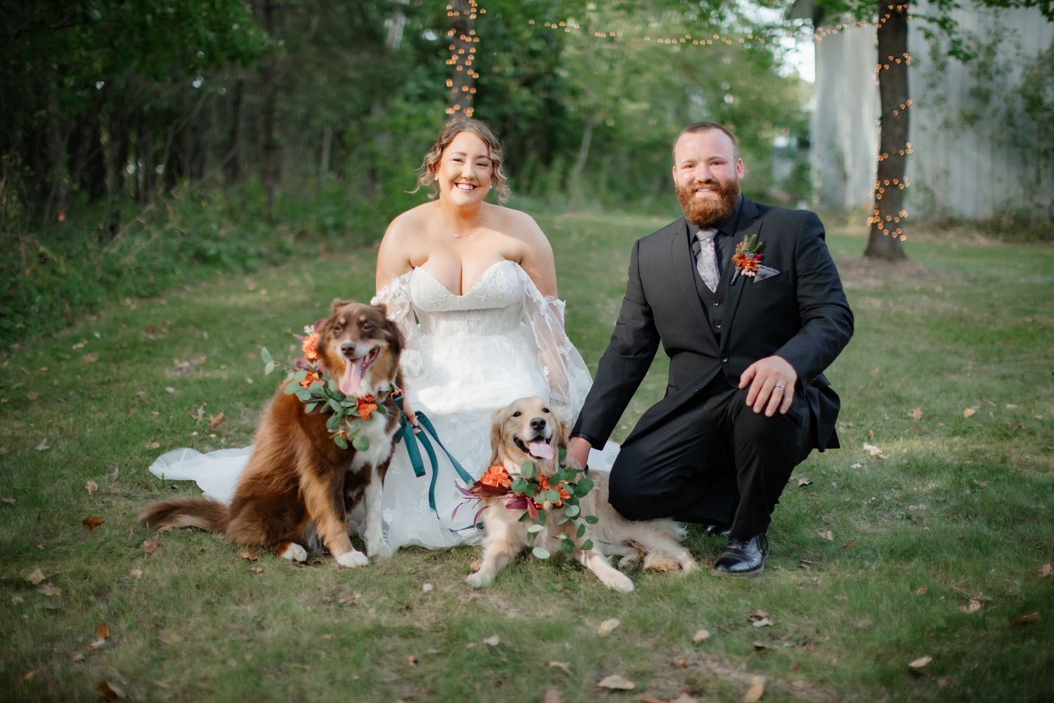 Wedding couple posing with their two happy dogs in a natural outdoor setting.