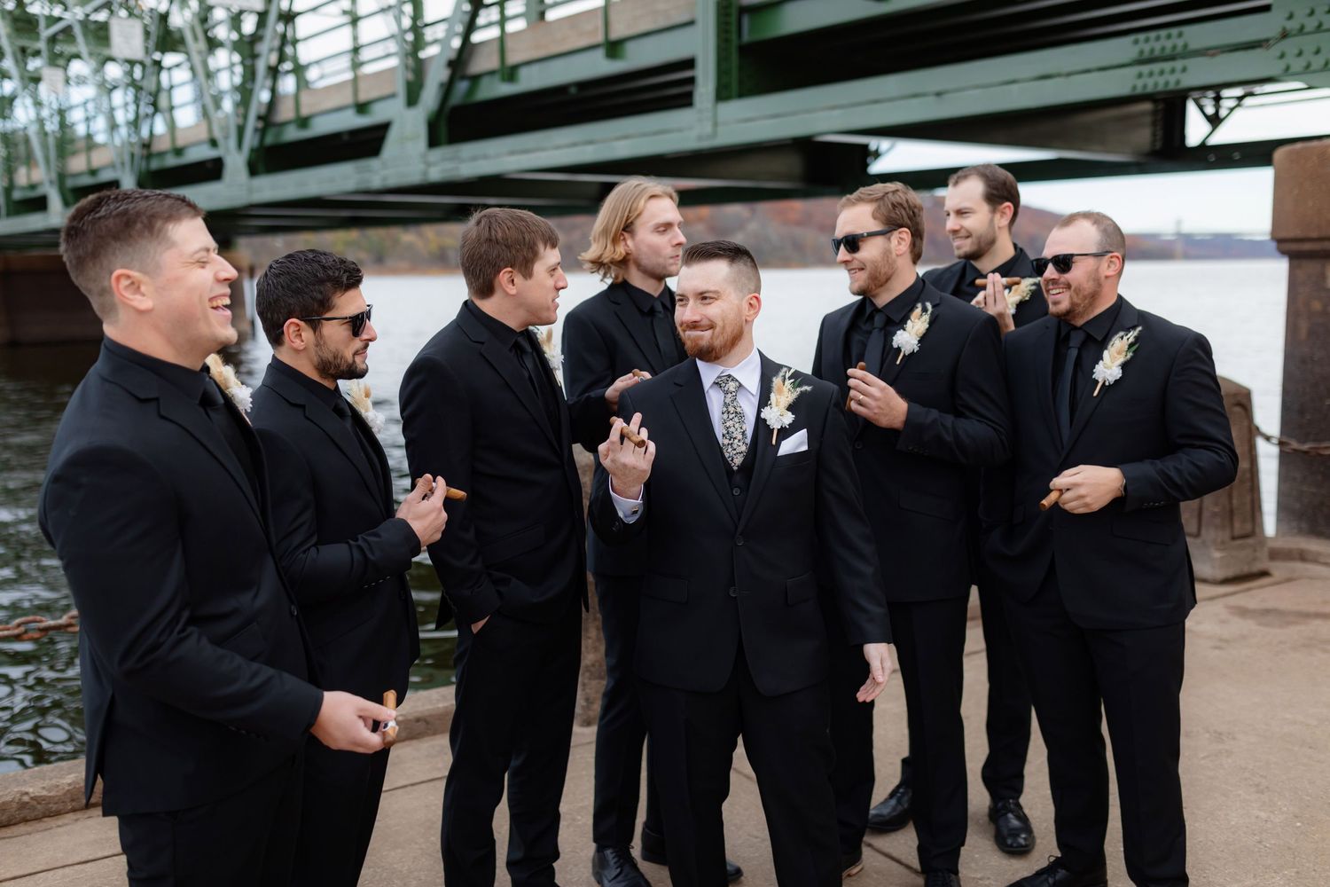 Groomsmen share laughs during candid moment at outdoor wedding venue.