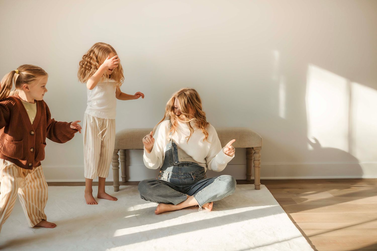 People in casual outfits dance and move together in a sunlit room with hardwood floors.