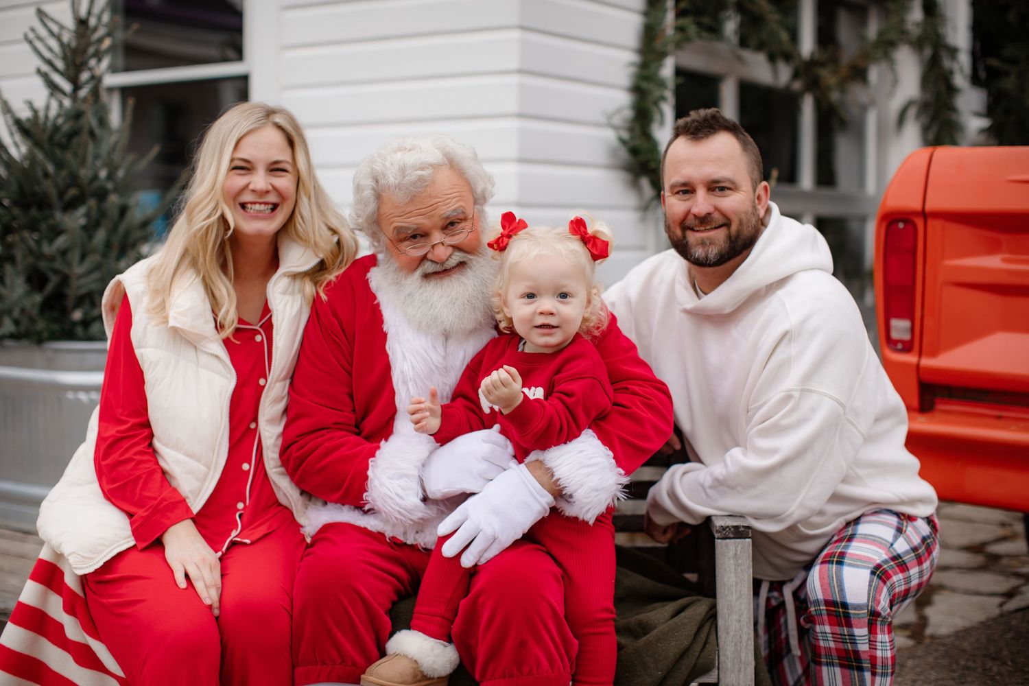 Family posing with Santa Claus in coordinated red and white outfits.