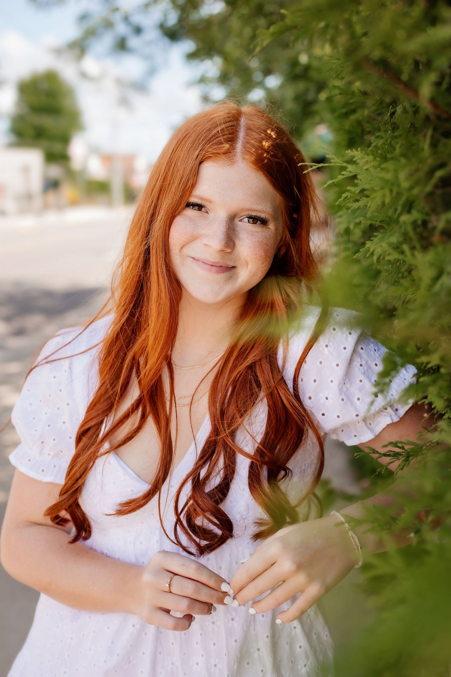 Outdoor portrait with white eyelet dress and natural greenery backdrop.