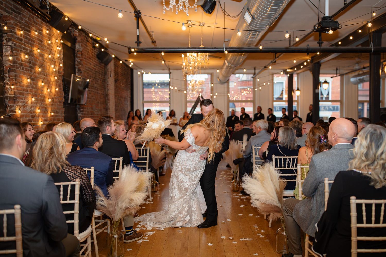 Wedding celebration in a rustic venue with fairy lights and dancing in the center aisle.