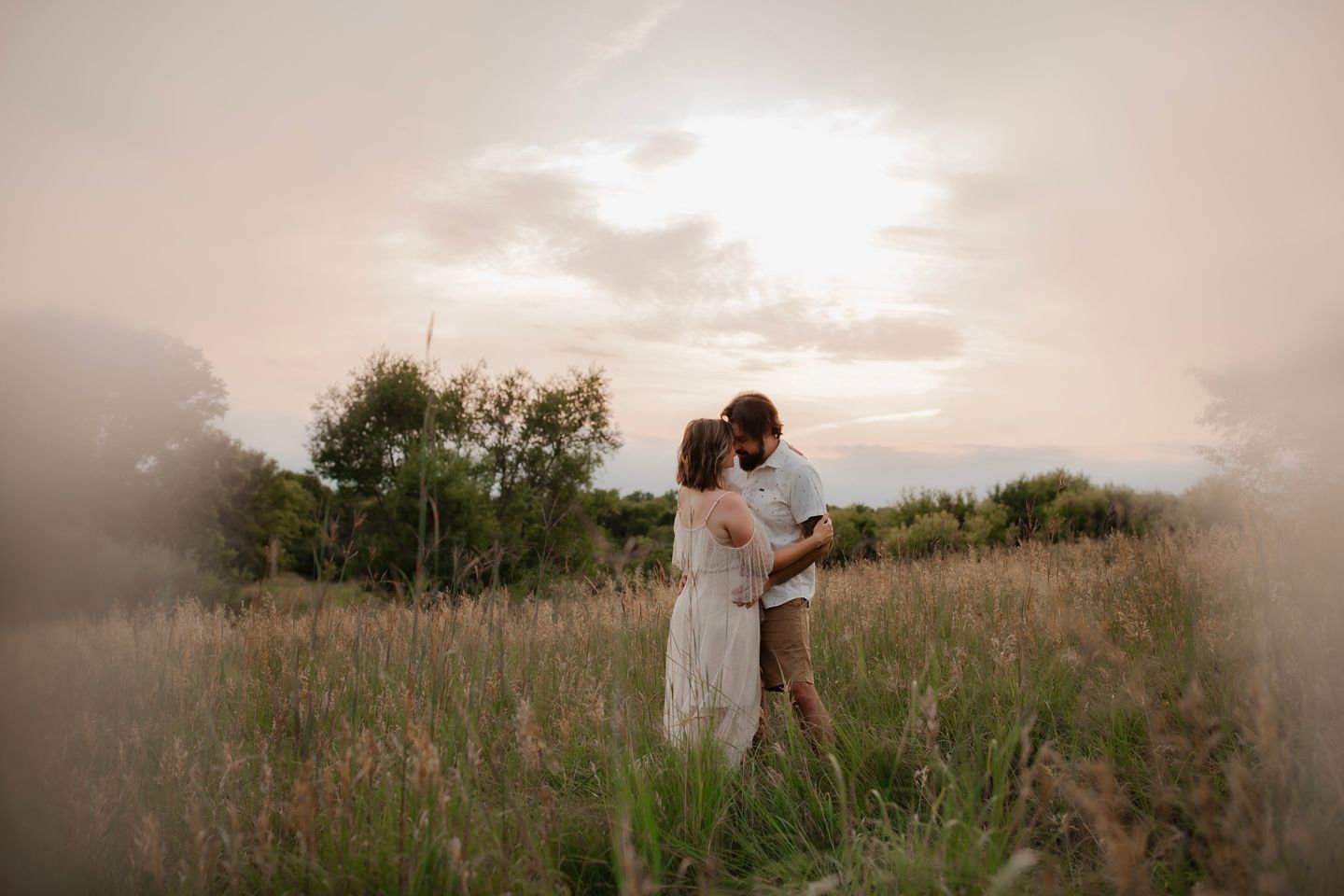Dreamy silhouette of couple embracing in misty field at dusk.