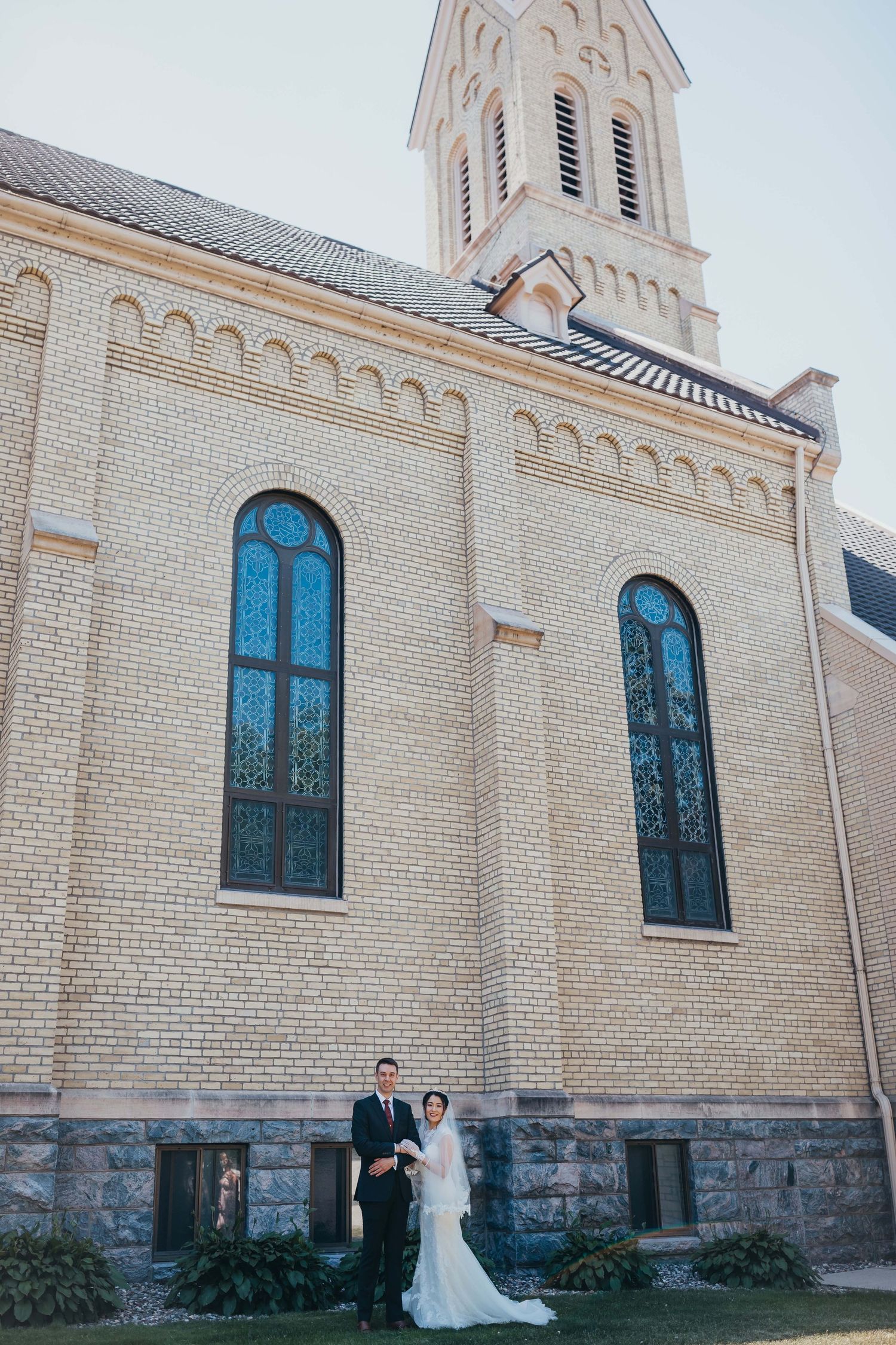 Architectural wedding photo showcasing Gothic church facade with couple in foreground.