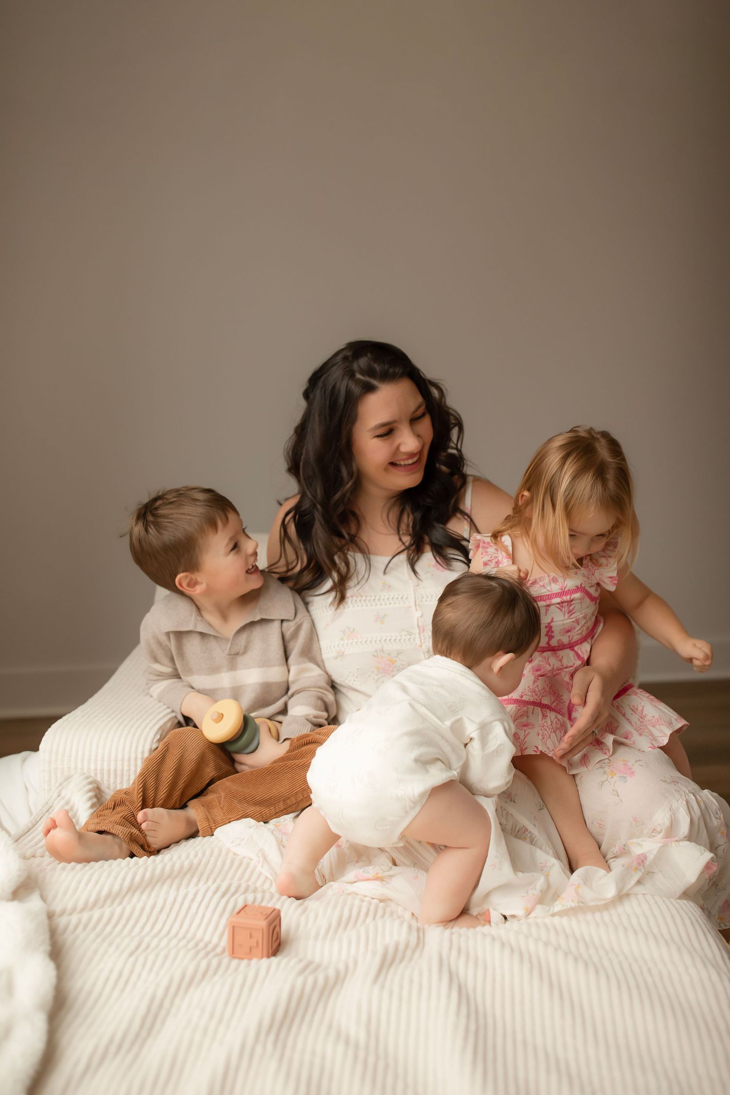 Sweet family moment captured in a sequence showing playful interactions on a white bed.