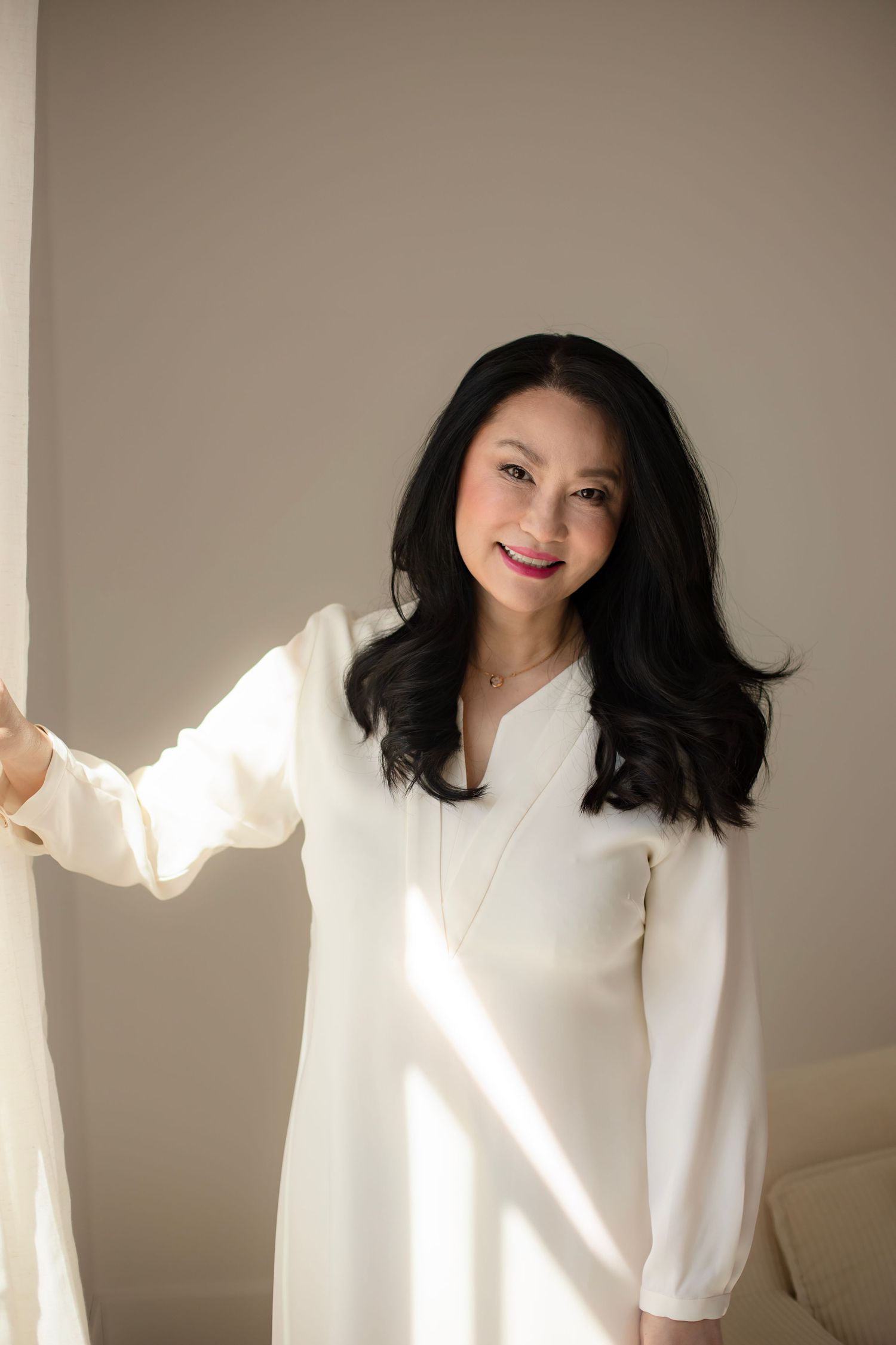 Multiple poses of someone wearing a flowing white sweater in front of a beige wall with dramatic lighting.