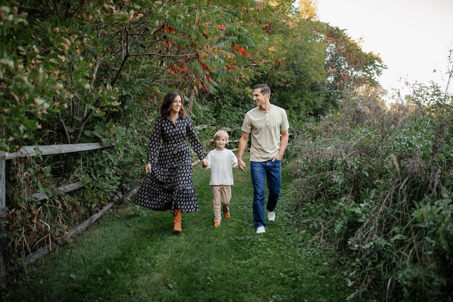 Family takes casual stroll together on nature path surrounded by lush greenery.