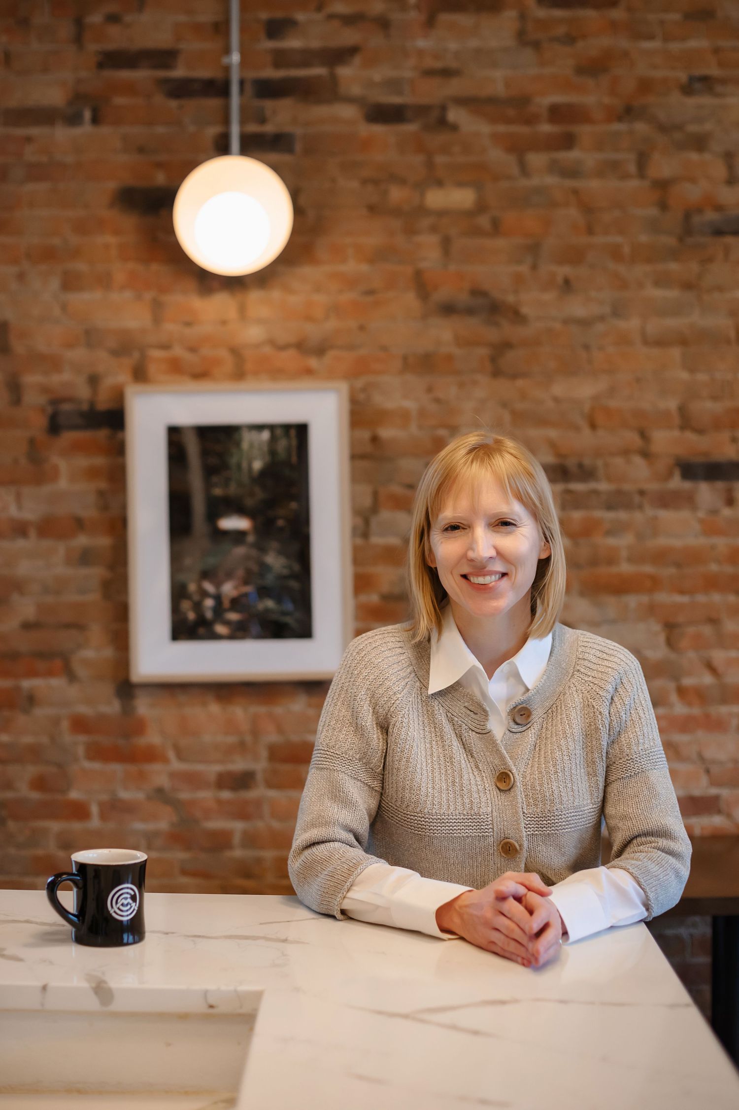 Interior cafe scene with exposed brick wall, pendant light, and casual business attire.