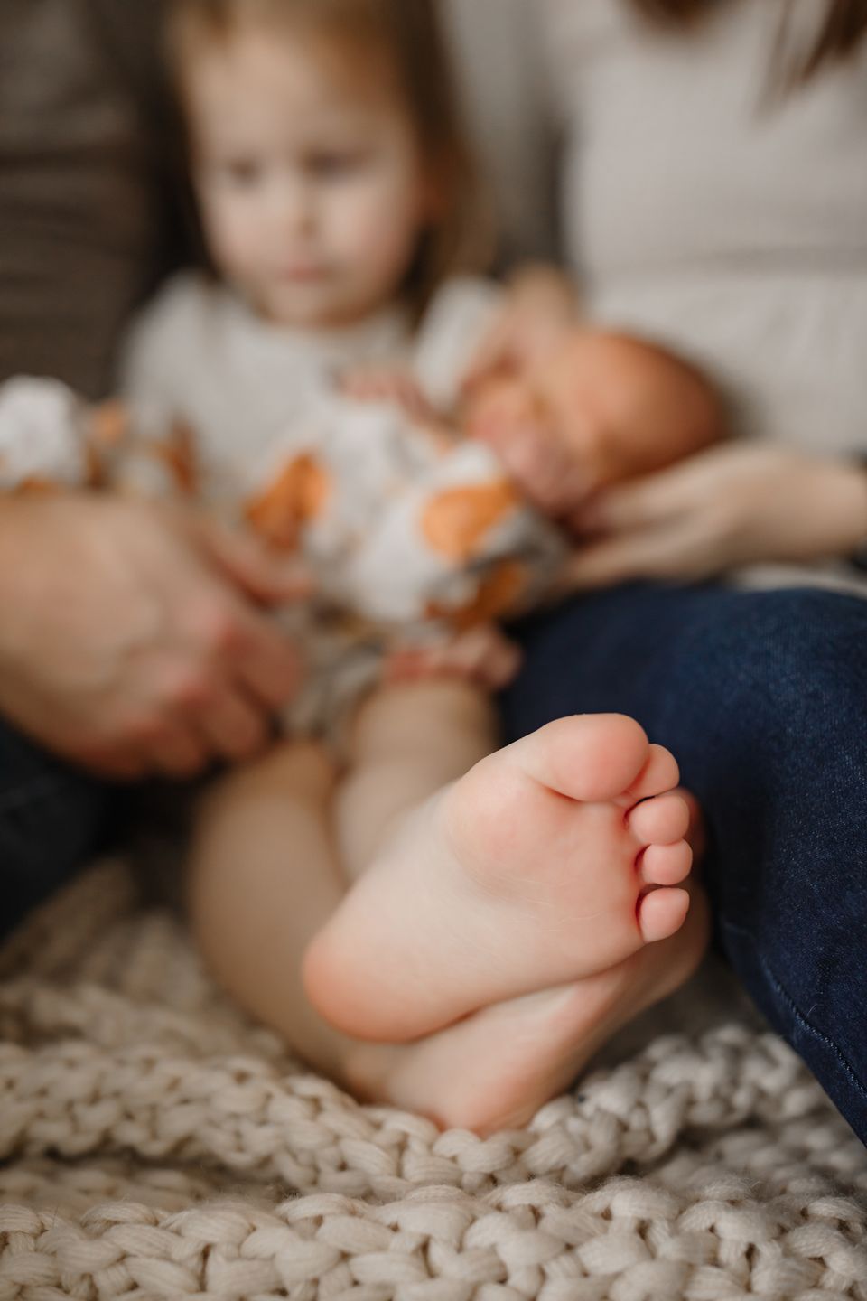 Close-up of tiny baby feet resting on chunky knit blanket.