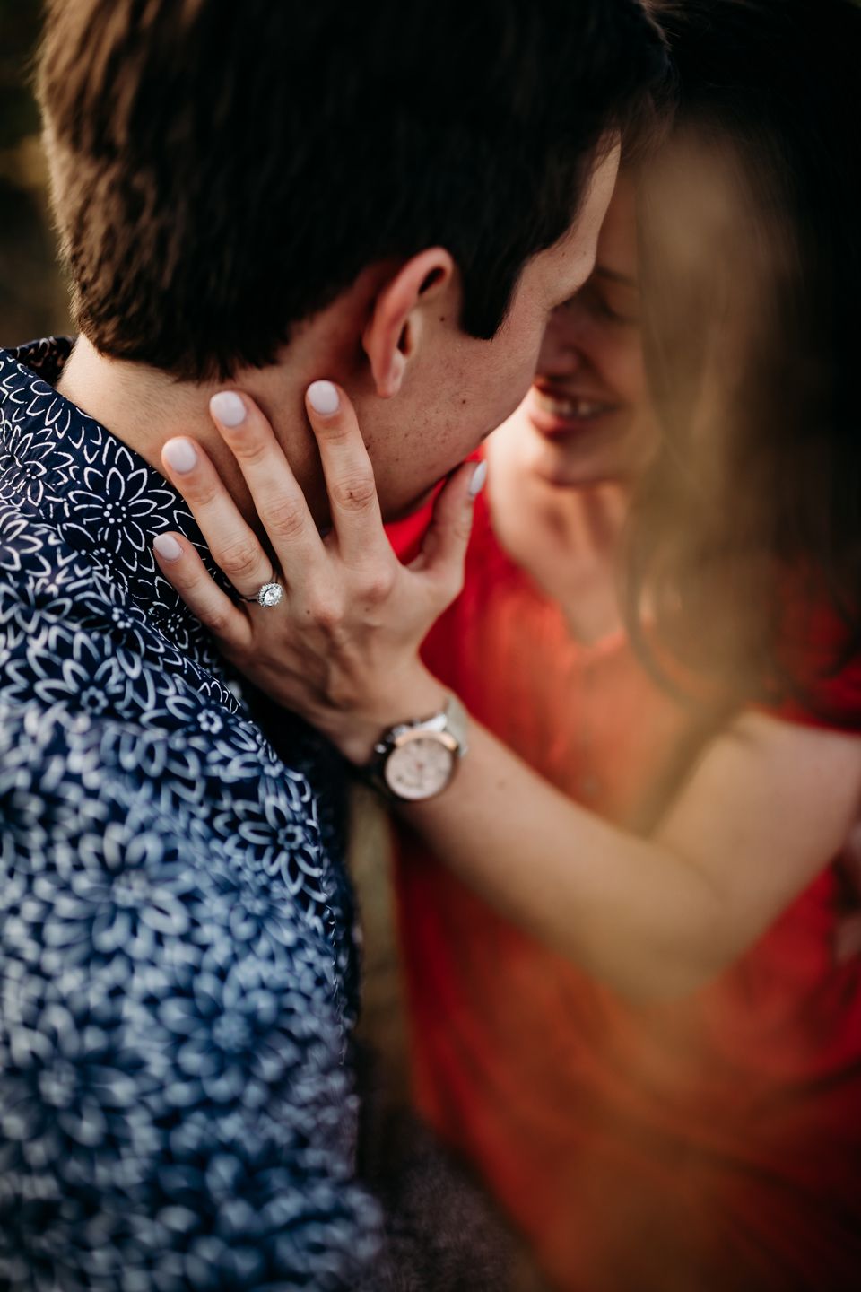 Close-up shot of romantic embrace showing engagement ring and intimate moment.