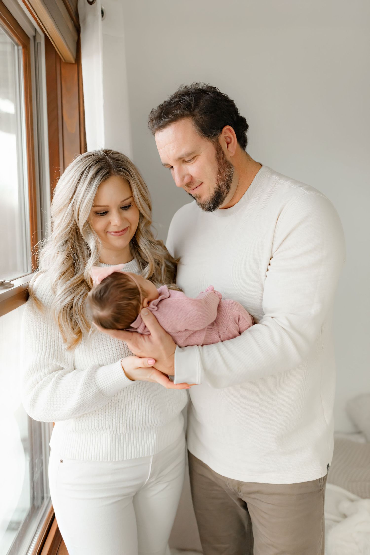 Family in white sweaters sharing tender moment by window.