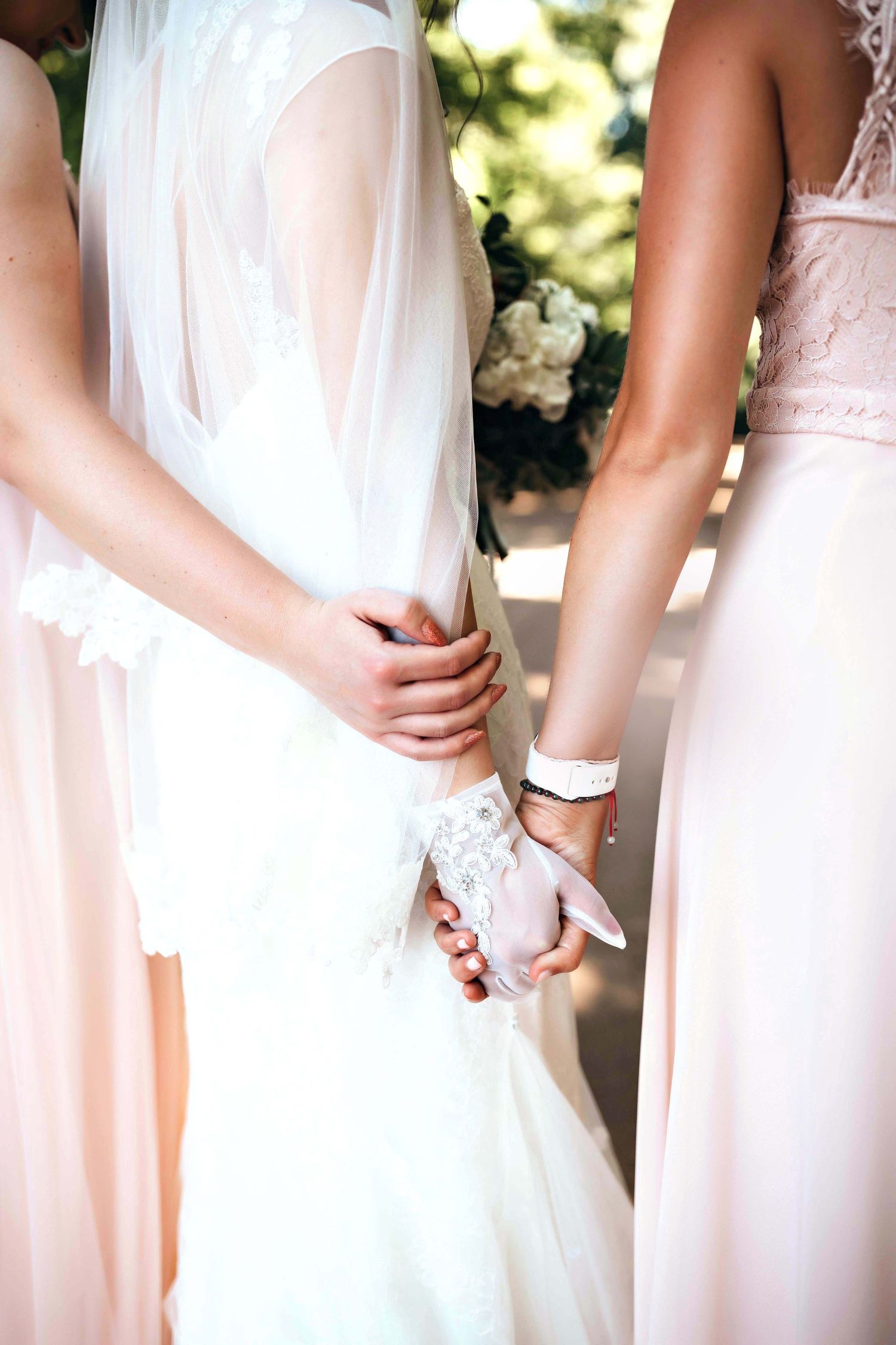 Close-up detail of wedding dress and bridesmaid gowns in soft blush tones.