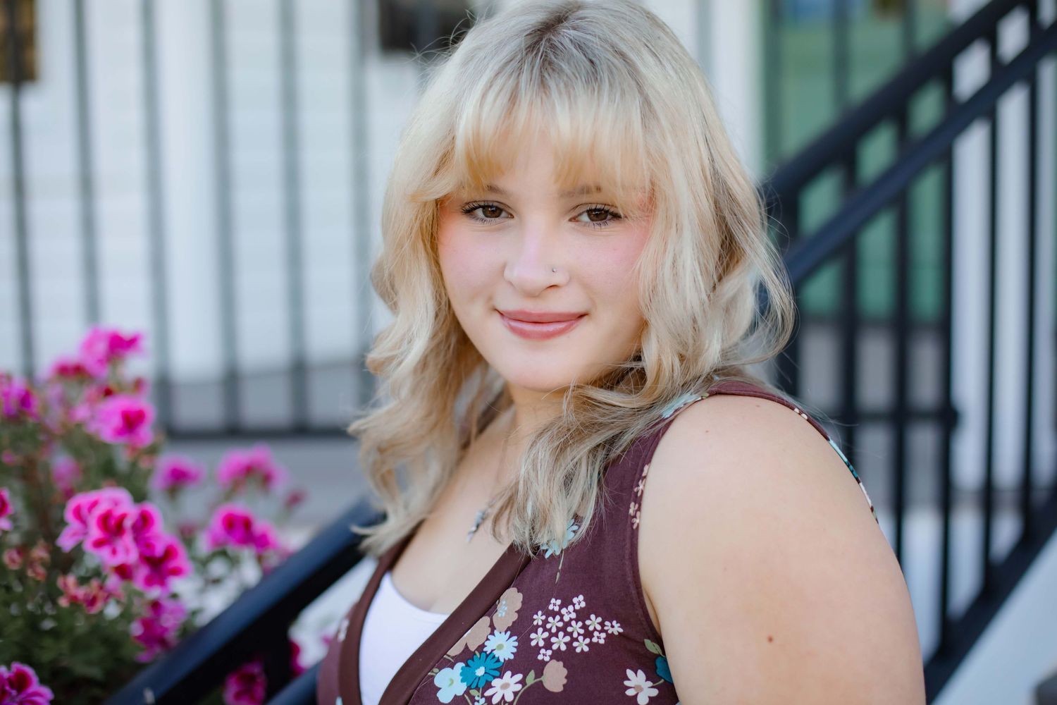 Portrait photo with bright pink flowers in the background on stone steps.