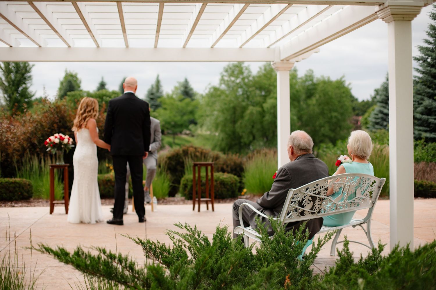 White pergola covered outdoor wedding venue with chairs set up for ceremony.