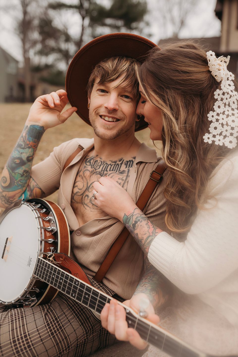 A couple shares an intimate moment outdoors while holding a banjo in warm vintage tones.