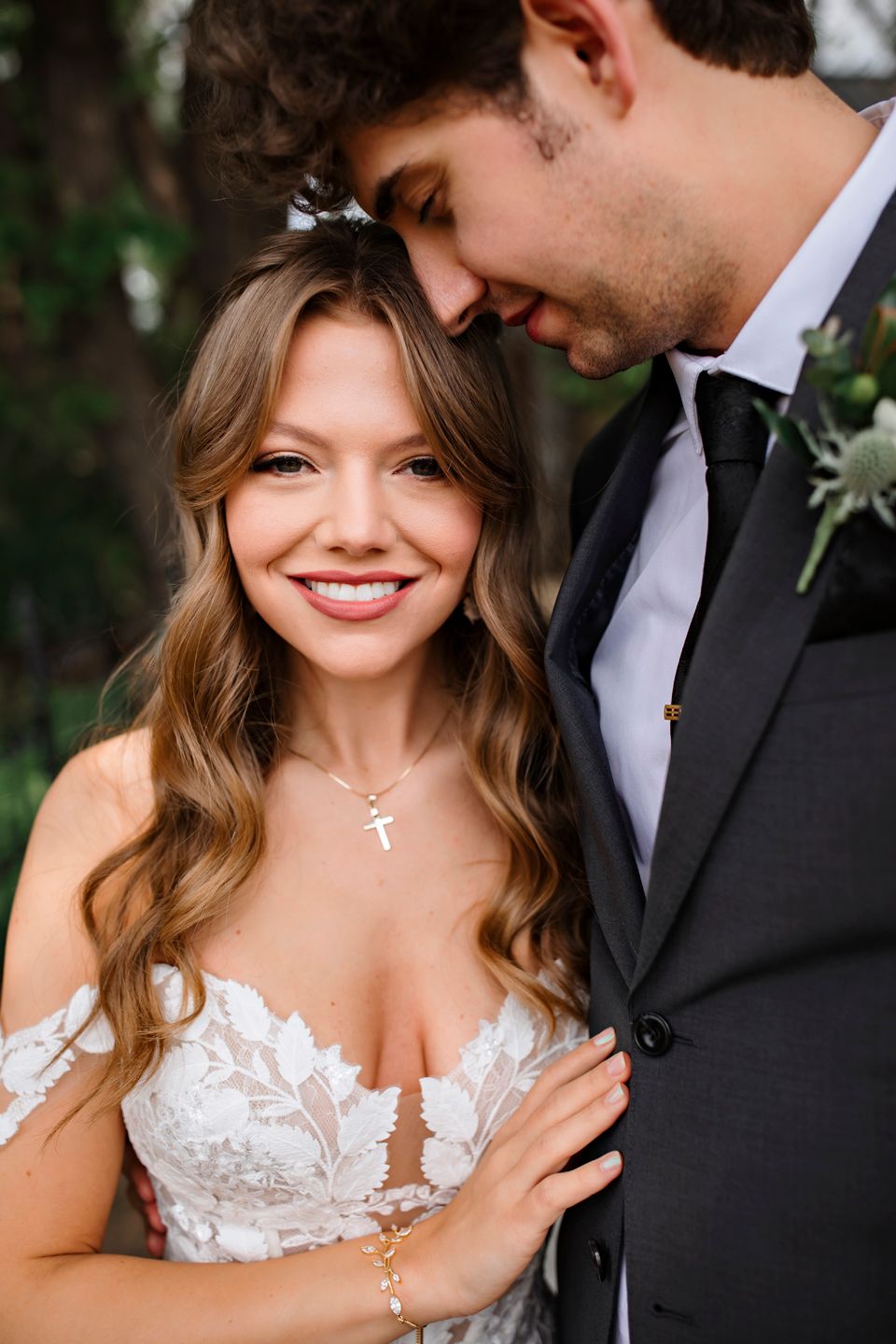 Intimate wedding portrait showing couple in formal attire against natural outdoor backdrop.