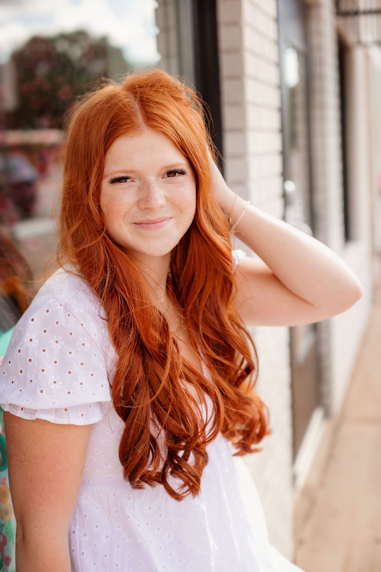 Portrait featuring flowing red hair and white eyelet dress in soft natural lighting.