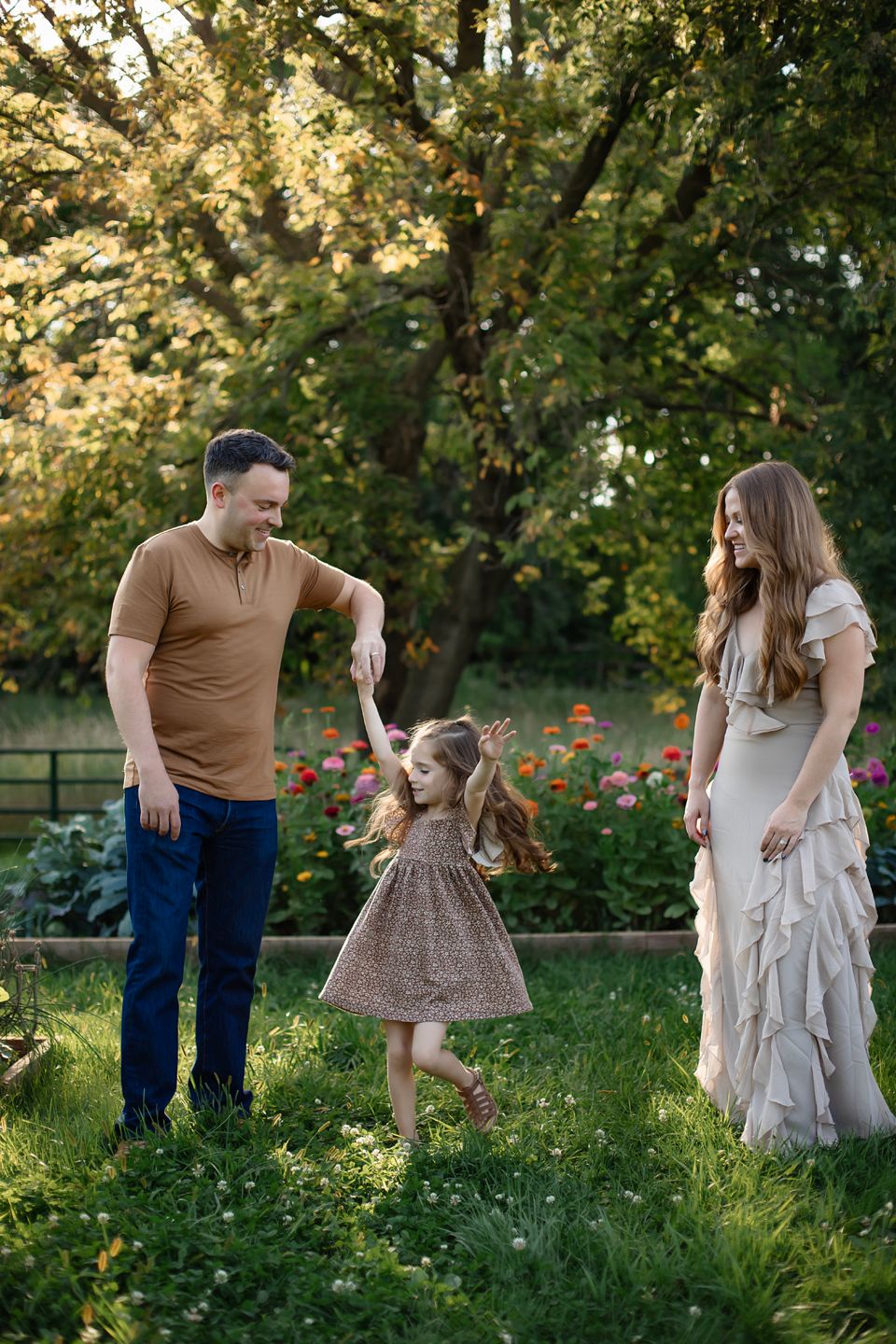A family enjoys a tender moment together in a garden with blooming flowers during golden hour.