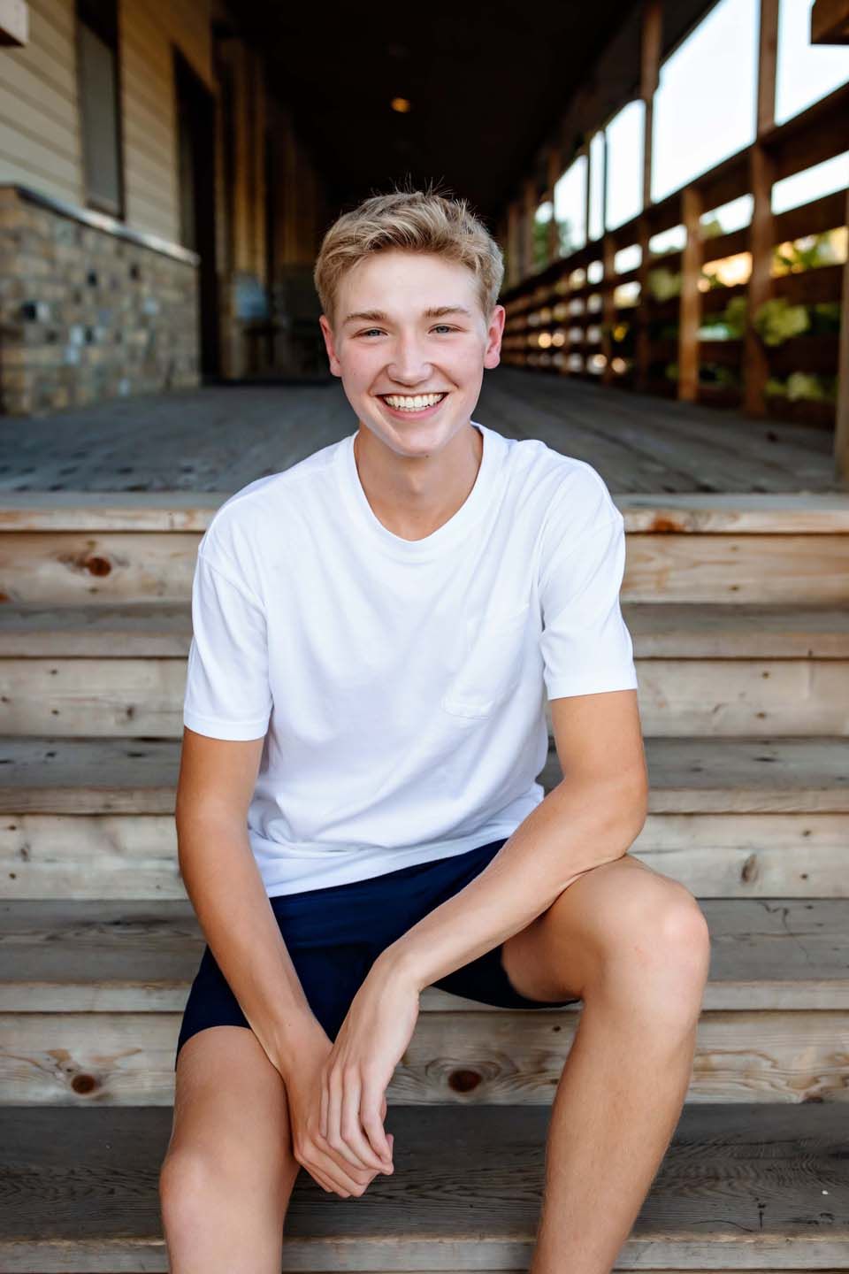 Casual outdoor portrait sitting on wooden steps wearing white t-shirt.