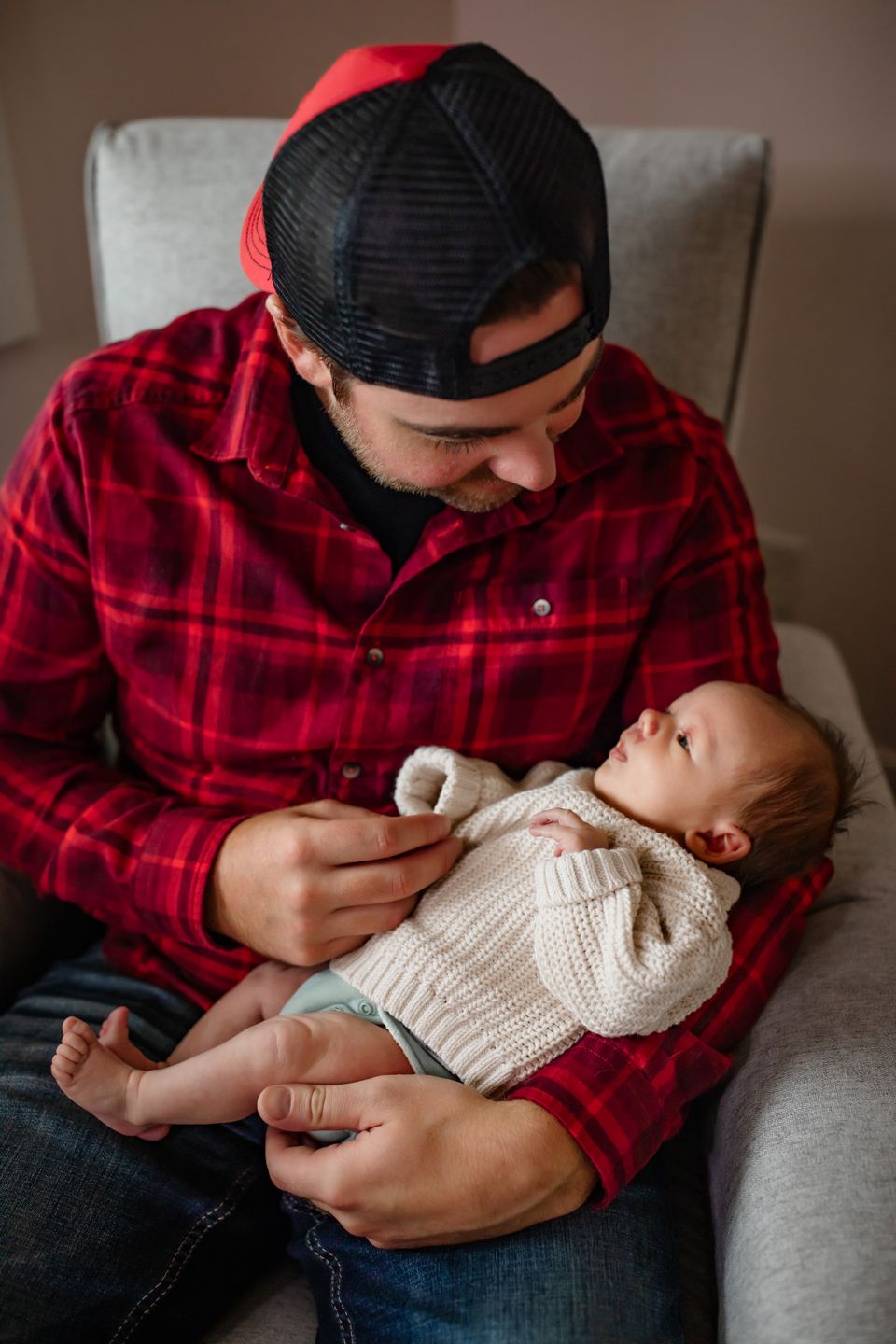 An intimate moment captured in a cozy grey armchair with warm lighting.