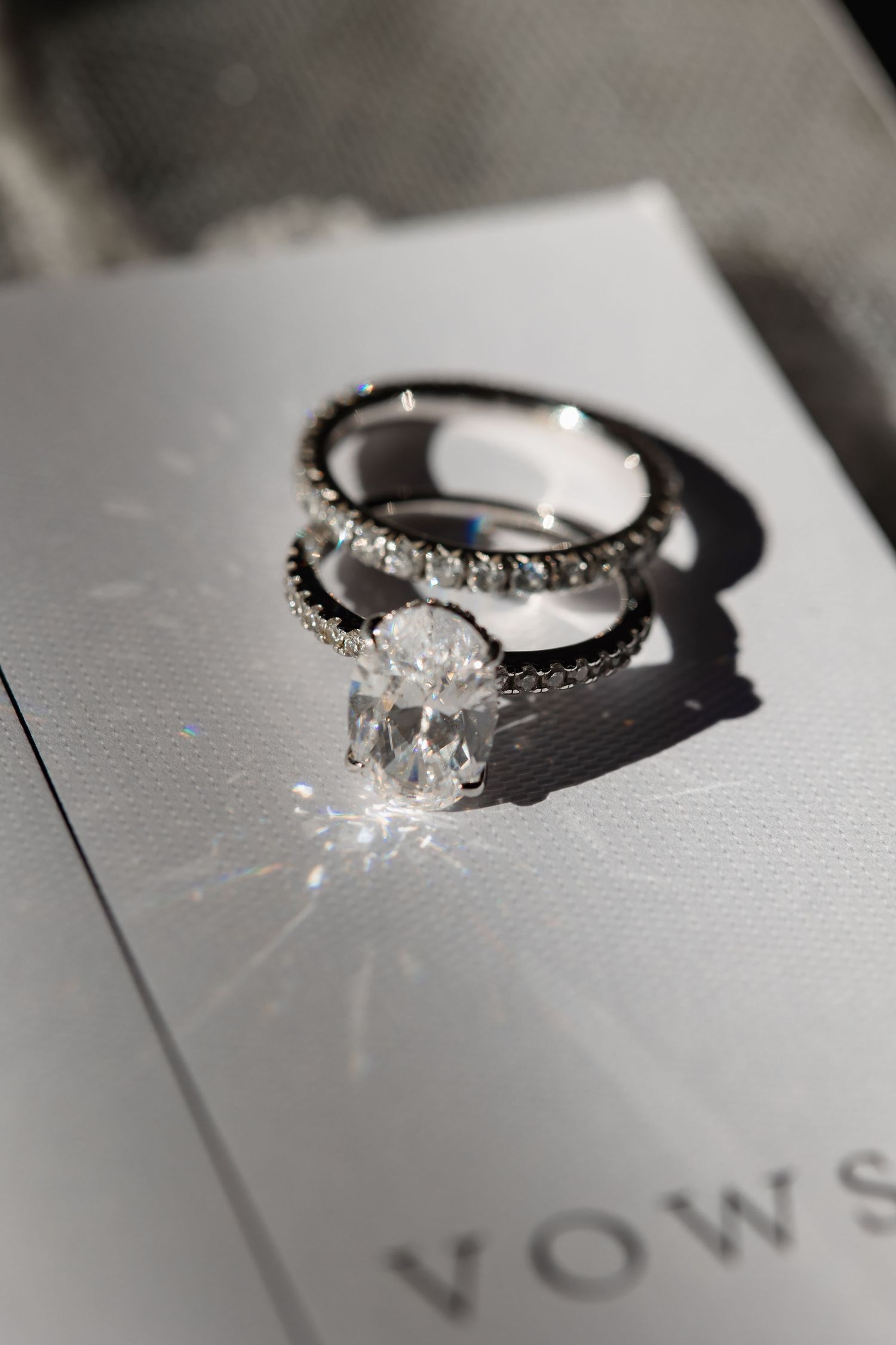 Diamond engagement ring and wedding band casting shadows on a vows booklet.