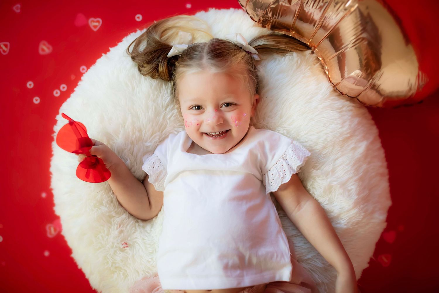 Cheerful portrait on white circular rug against red background with heart decorations.