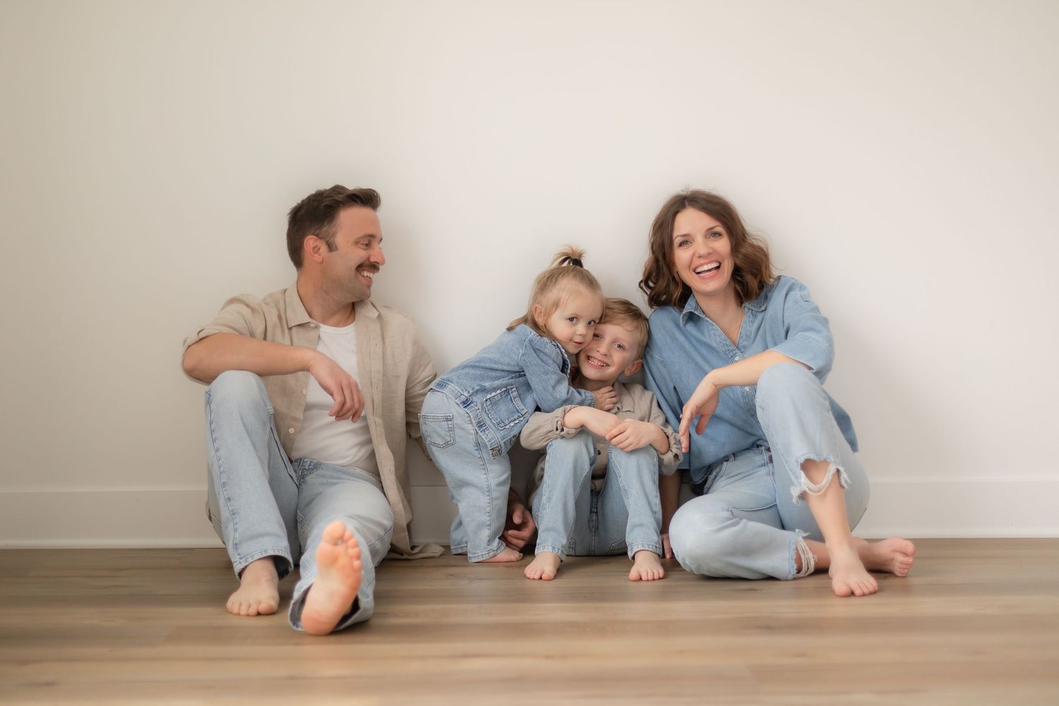 People in casual denim outfits sitting on floor against white wall in progressive sequence of poses.